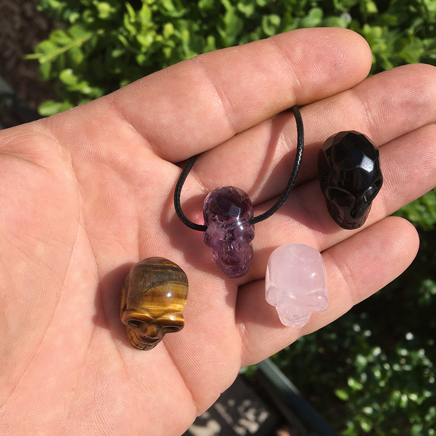 Pendentif en forme de crâne, symbole de la connaissance ! De 18 millimètres de hauteur x 16 mm de largeur. Pierre au choix : Améthyste, Obsidienne, Quartz rose, Oeil de tigre. Vendu avec cordon noir réglable offert, parfait !