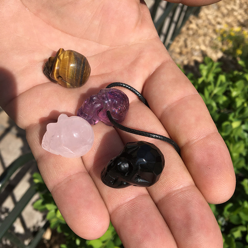 Pendentif en forme de crâne, symbole de la connaissance ! De 18 millimètres de hauteur x 16 mm de largeur. Pierre au choix : Améthyste, Obsidienne, Quartz rose, Oeil de tigre. Vendu avec cordon noir réglable offert, parfait !