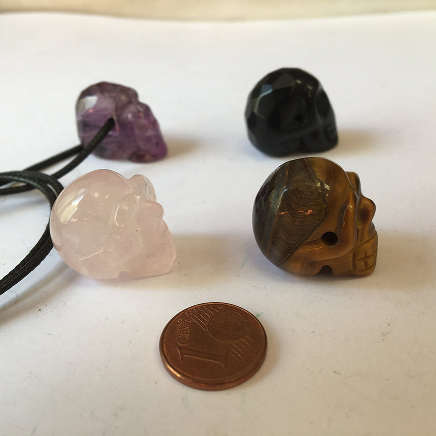 Pendentif en forme de crâne, symbole de la connaissance ! De 18 millimètres de hauteur x 16 mm de largeur. Pierre au choix : Améthyste, Obsidienne, Quartz rose, Oeil de tigre. Vendu avec cordon noir réglable offert, parfait !