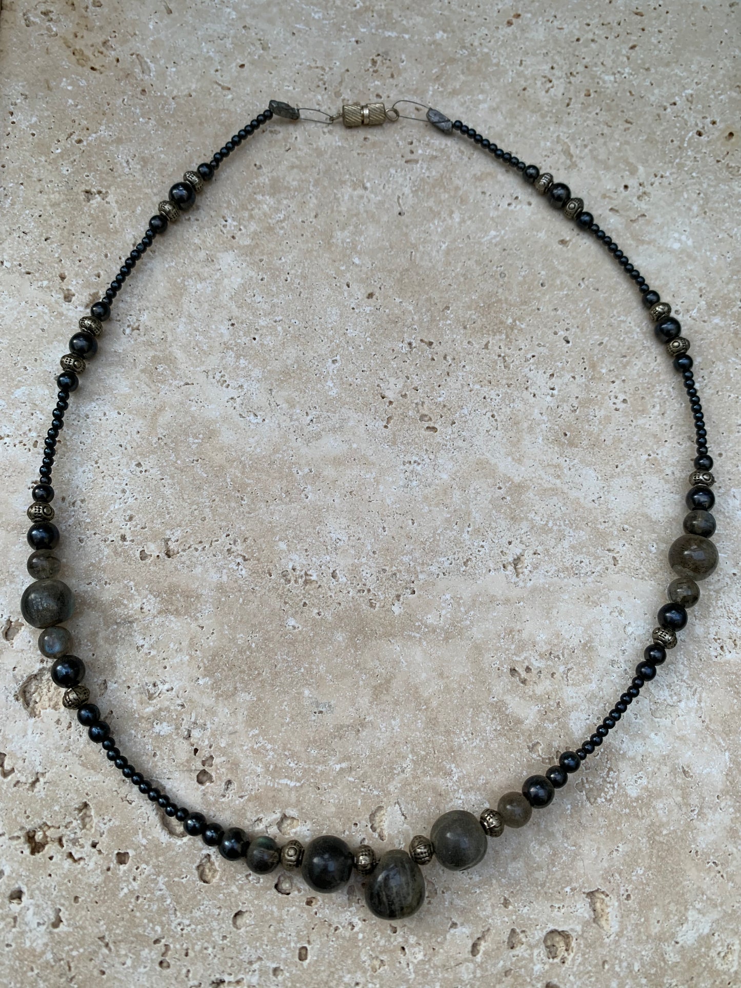 Labradorite avec hématite, 'collier/ chute de perle', de forme ronde de 2 à 10 millimètres de diamètre. 45 centimètres de longueur, fermoir à vis. Très belle pièce montée par Gem & Zen !