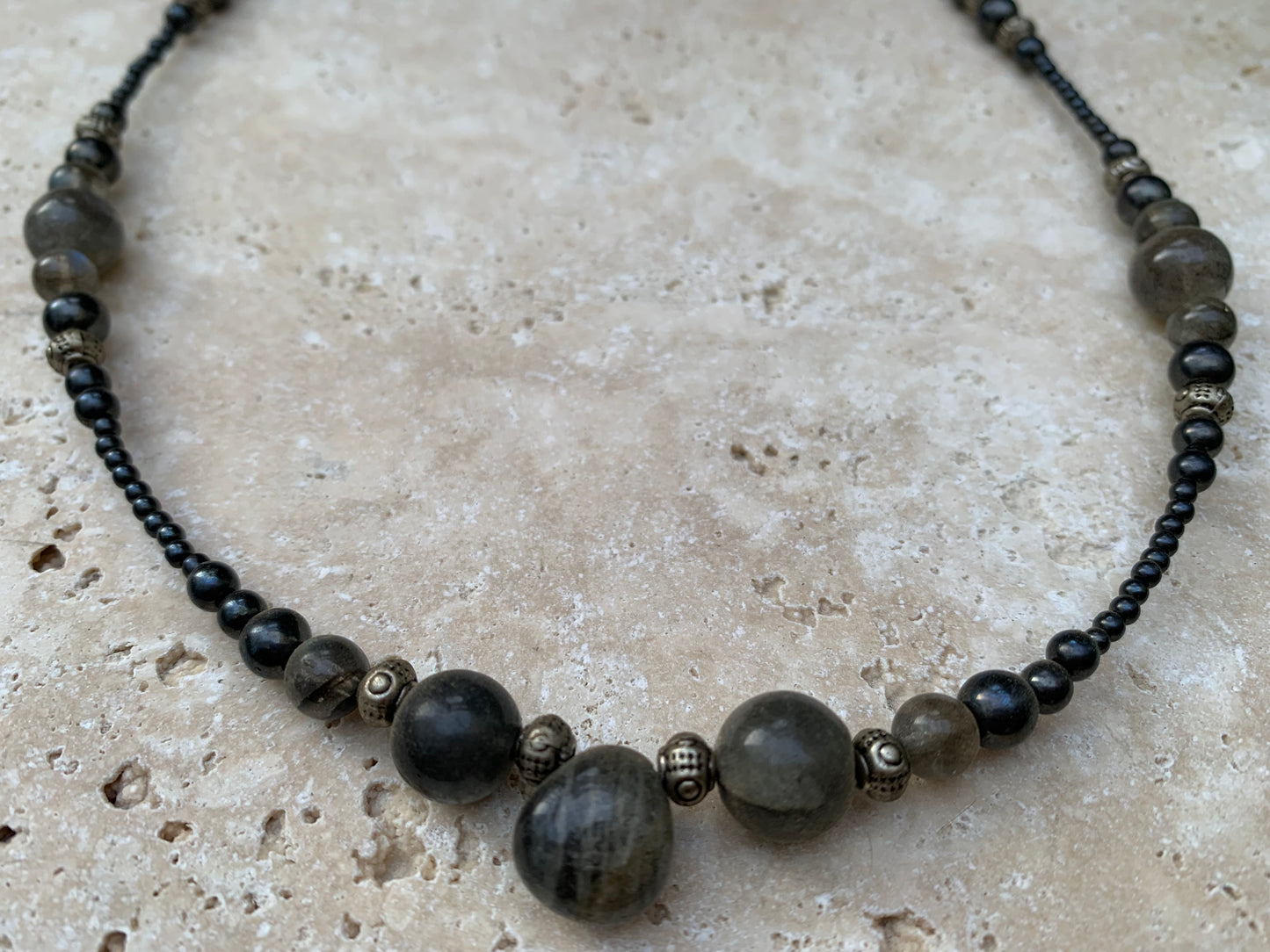 Labradorite avec hématite, 'collier/ chute de perle', de forme ronde de 2 à 10 millimètres de diamètre. 45 centimètres de longueur, fermoir à vis. Très belle pièce montée par Gem & Zen !