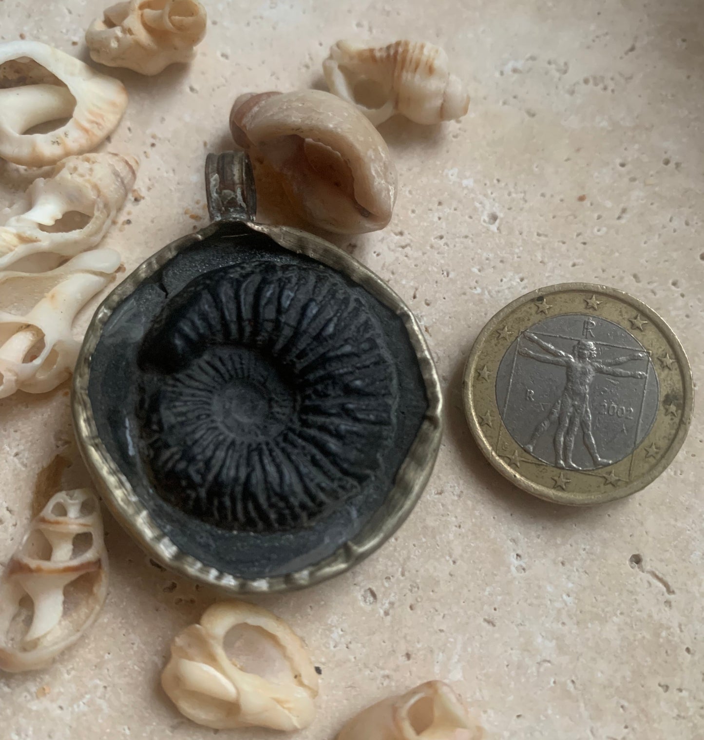 Ammonite fossile du Népal, taille de 45x35x12 millimètres. Pièce authentique et unique, révélant les spirales naturelles et les motifs fascinants de ce fossile. Livré avec cordon coulissant, prêt à porté ou à offrir !