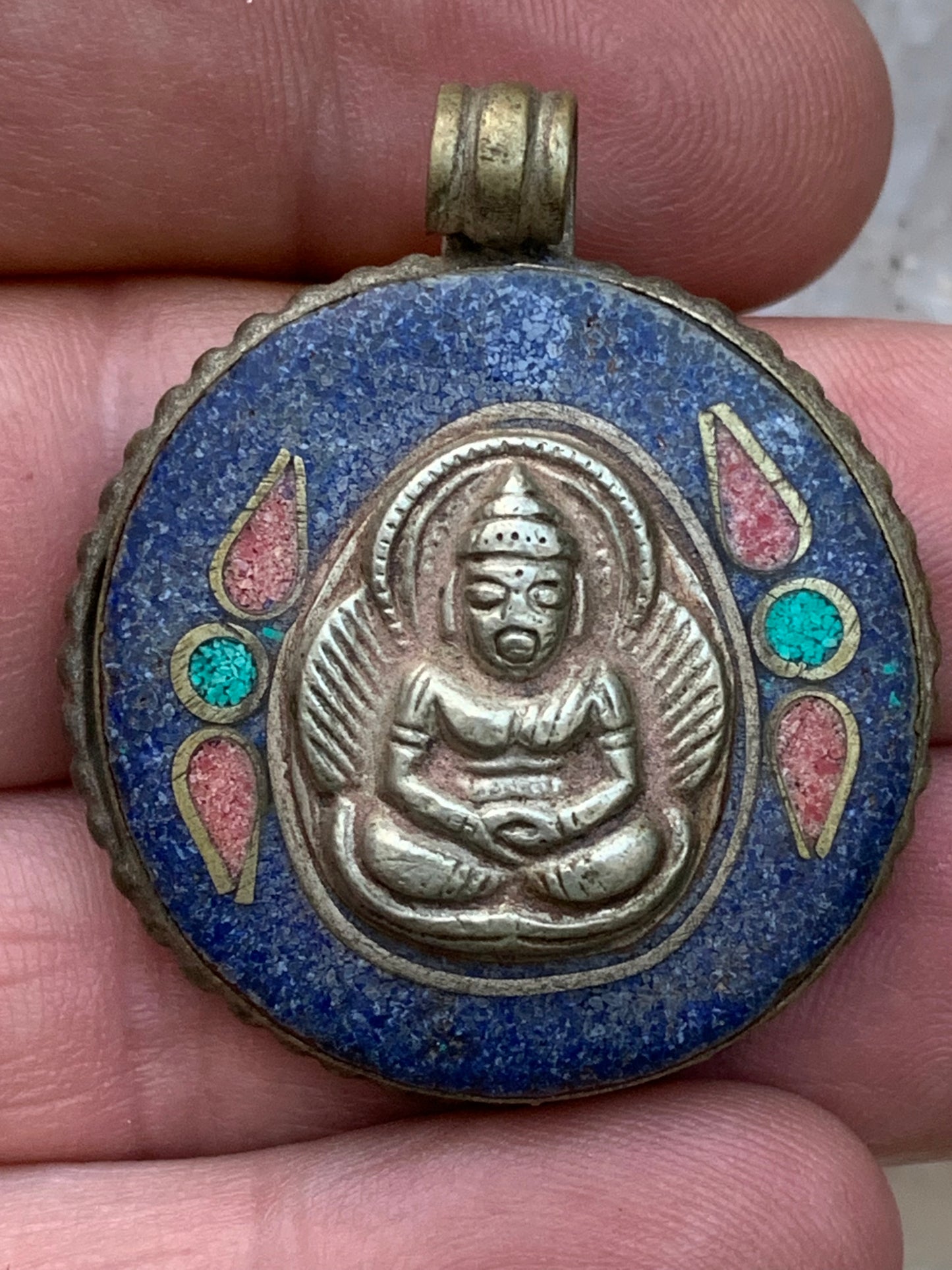 Bouddha, pendentif en lapis lazuli, corail et turquoise sur métal ton argent de 35 millimètres de diamètre. Avec de magnifiques gravures sur la face arrière. Livré avec cordon coulissant (offert), prêt à porté ou à offrir, parfait !