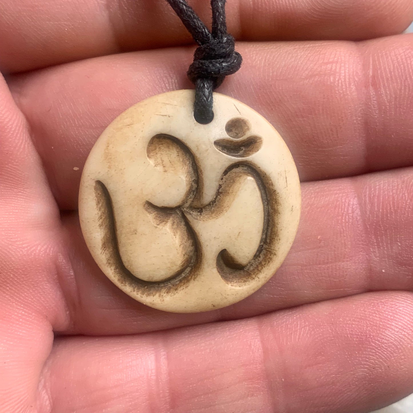 Pendentif artisanal du Népal avec symbole Om, sculpté dans de l’os, de 30 millimètres de diamètre x 4 mm d'épaisseur. Vendu avec cordon noir réglable offert, parfait !
