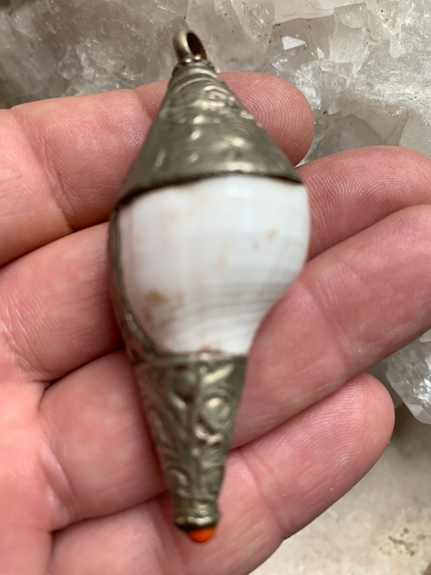 Pendentif artisanal du Népal en coquillage sertis en métal avec de jolies gravures et une perle de corail ! De 65 millimètres de hauteur x 28 mm de diamètre. Vendu avec cordon noir réglable offert, parfait !
