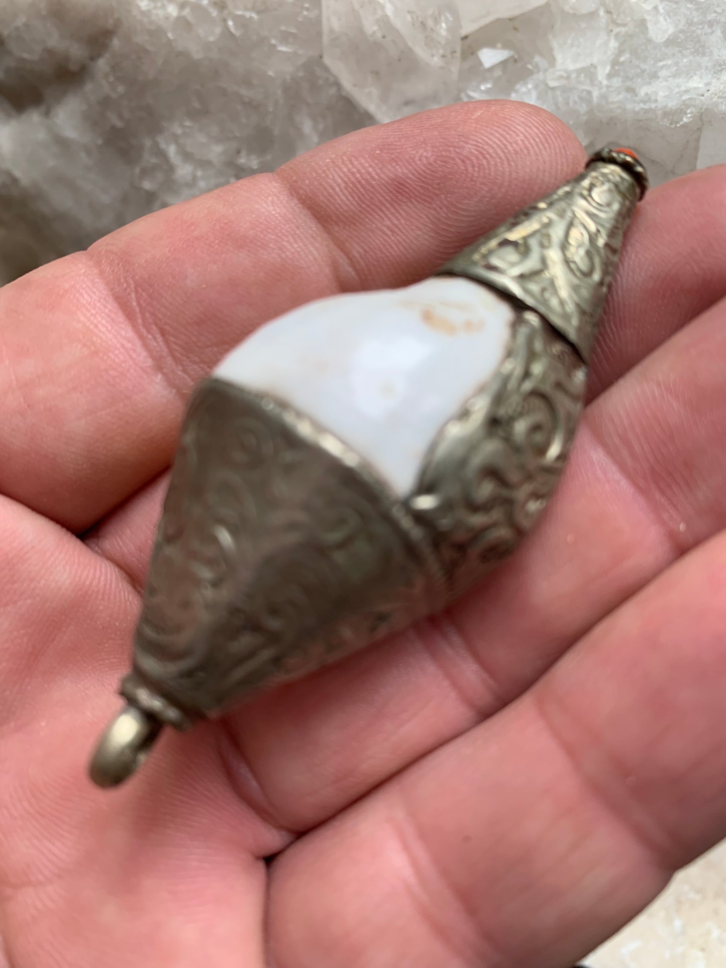 Pendentif artisanal du Népal en coquillage sertis en métal avec de jolies gravures et une perle de corail ! De 65 millimètres de hauteur x 28 mm de diamètre. Vendu avec cordon noir réglable offert, parfait !