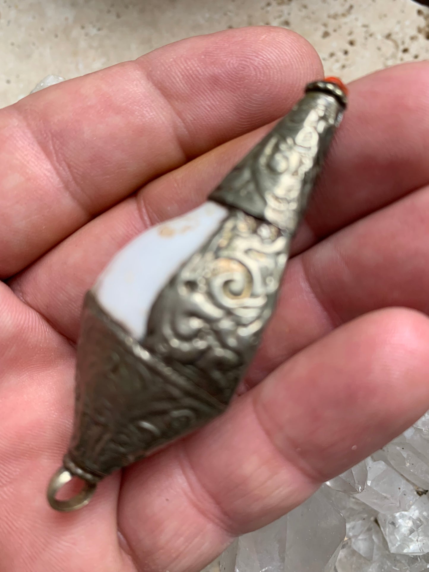 Pendentif artisanal du Népal en coquillage sertis en métal avec de jolies gravures et une perle de corail ! De 65 millimètres de hauteur x 28 mm de diamètre. Vendu avec cordon noir réglable offert, parfait !