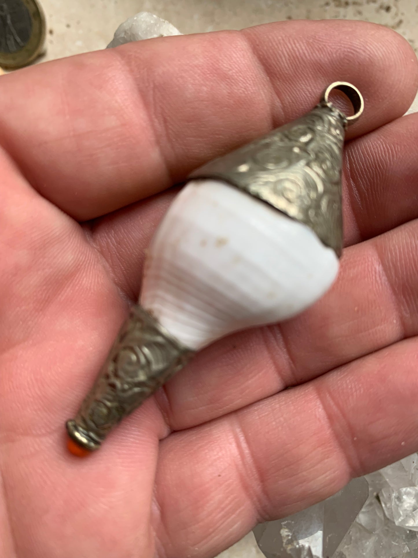 Pendentif artisanal du Népal en coquillage sertis en métal avec de jolies gravures et une perle de corail ! De 65 millimètres de hauteur x 28 mm de diamètre. Vendu avec cordon noir réglable offert, parfait !