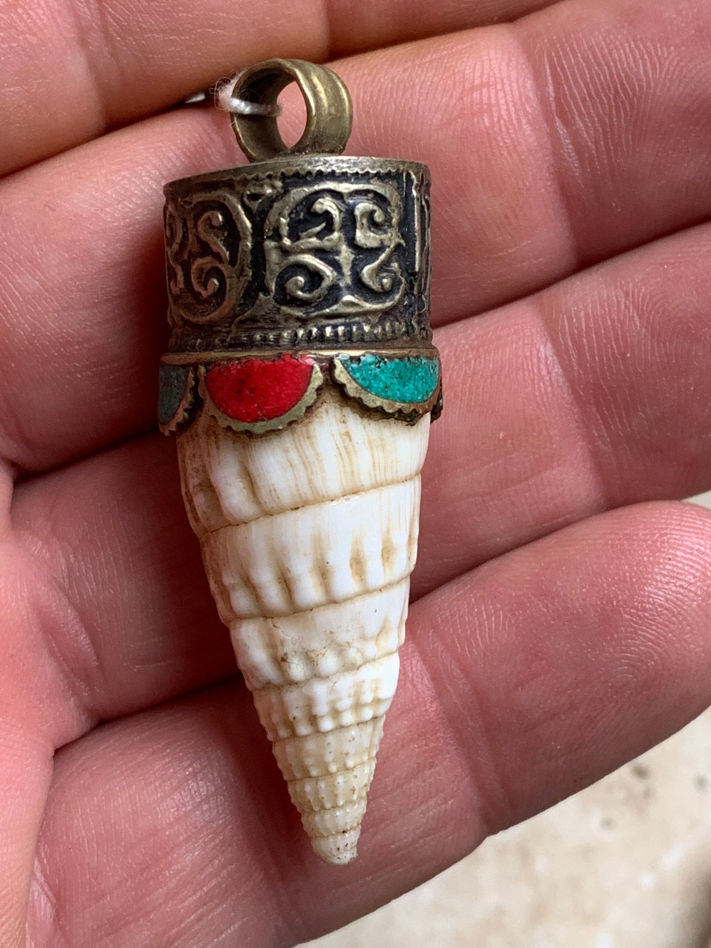 Pendentif artisanal du Népal en coquillage sertis en métal avec de jolies gravures et de la turquoise avec du corail ! De 53 millimètres de hauteur x 18 mm de diamètre. Vendu avec cordon noir réglable offert, parfait !
