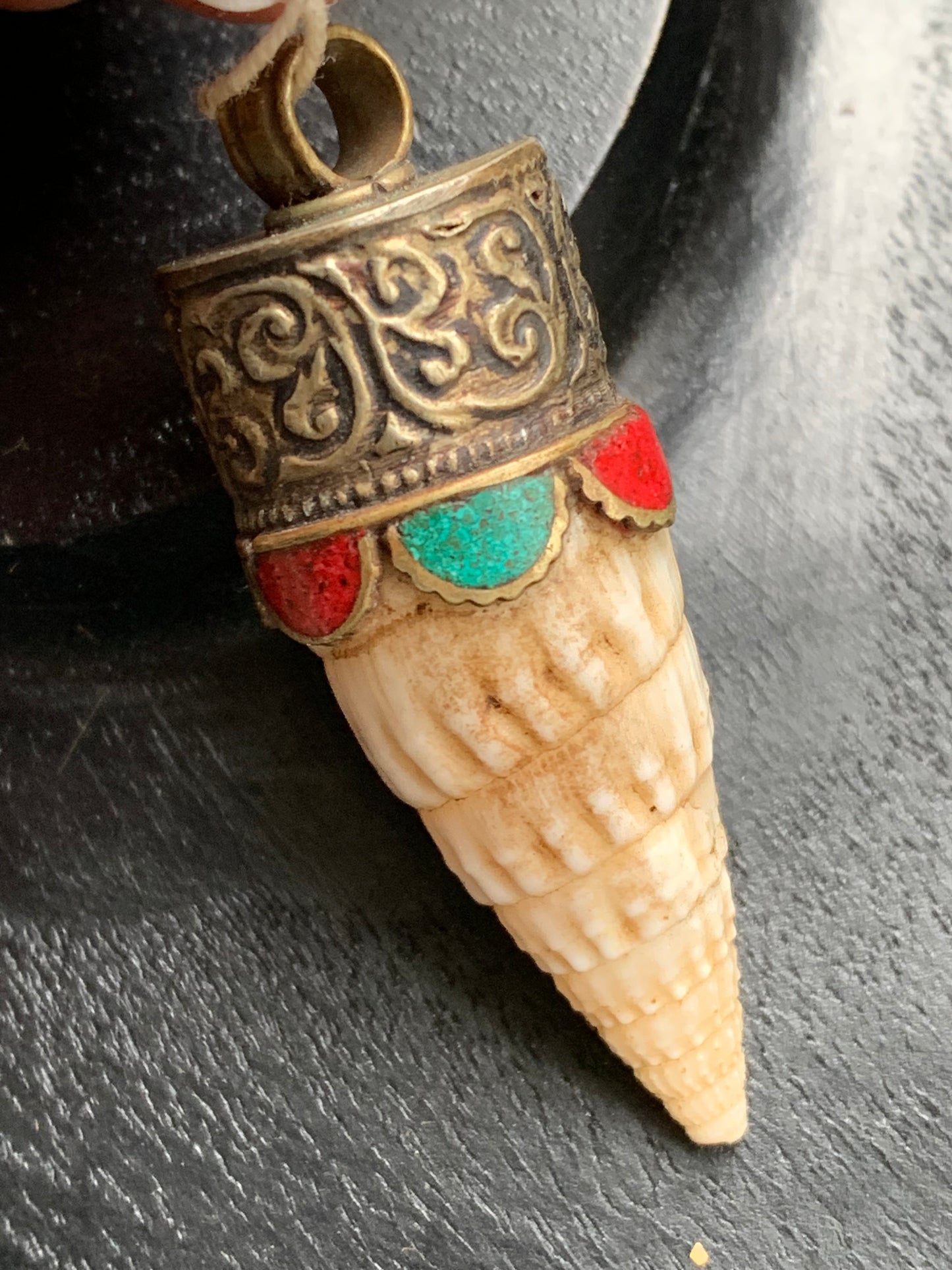 Pendentif artisanal du Népal en coquillage sertis en métal avec de jolies gravures et de la turquoise avec du corail ! De 53 millimètres de hauteur x 18 mm de diamètre. Vendu avec cordon noir réglable offert, parfait !