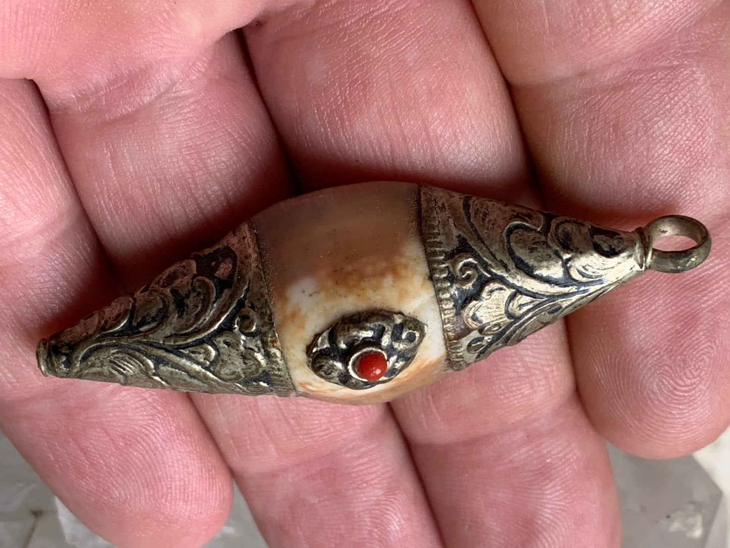 Pendentif artisanal du Népal en coquillage sertis en métal avec de jolies gravures et une perle de corail ! De 60 millimètres de hauteur x 23 mm de largeur x 16 d'épaisseur. Vendu avec cordon noir réglable offert, parfait !