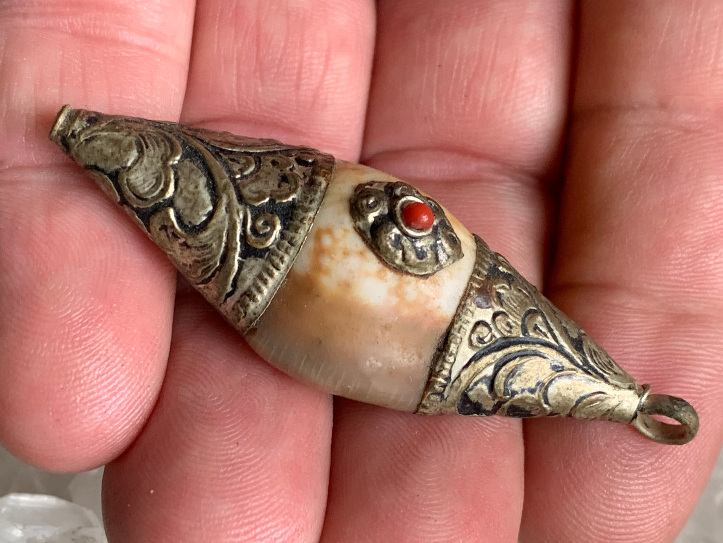Pendentif artisanal du Népal en coquillage sertis en métal avec de jolies gravures et une perle de corail ! De 60 millimètres de hauteur x 23 mm de largeur x 16 d'épaisseur. Vendu avec cordon noir réglable offert, parfait !