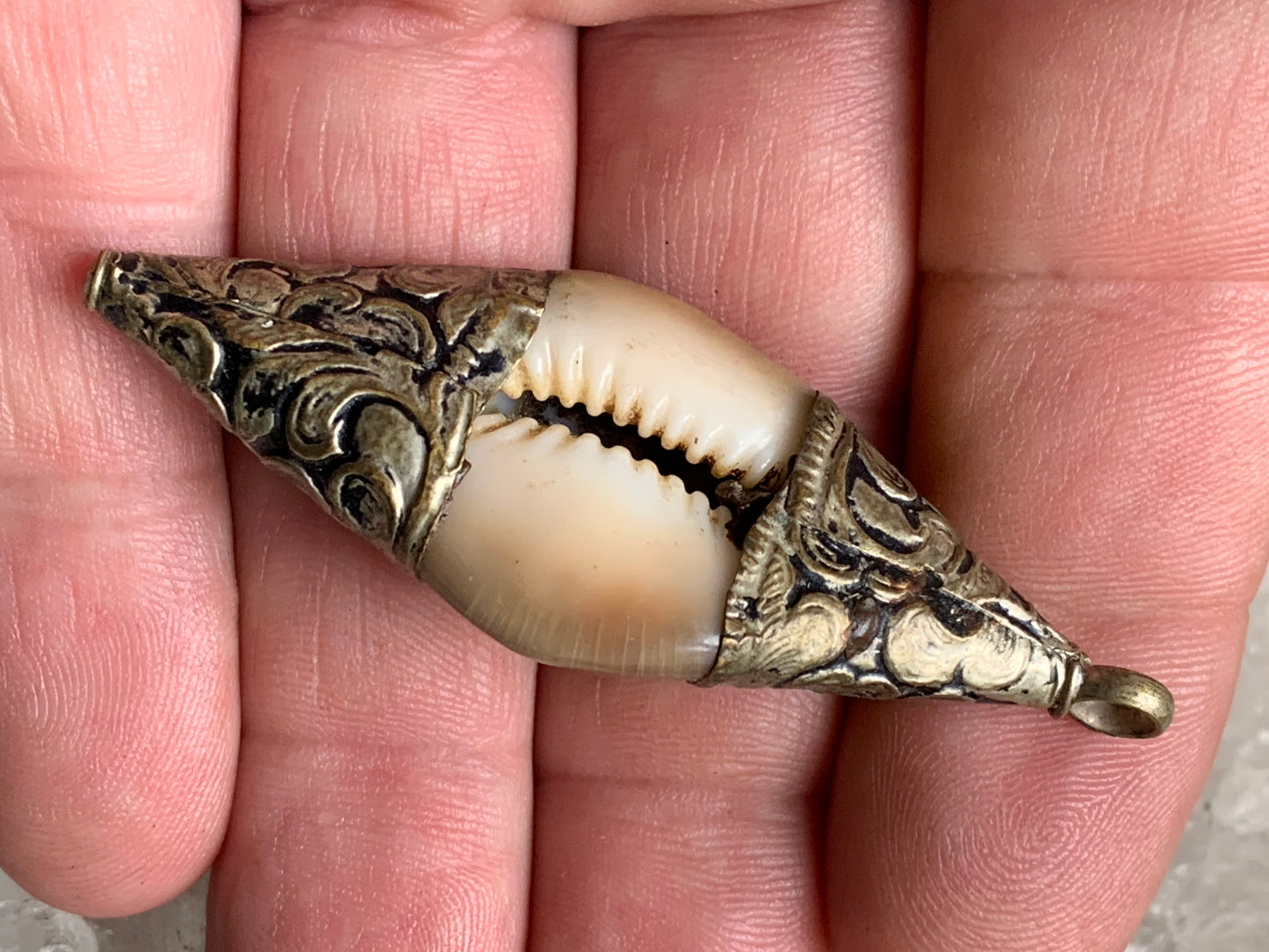 Pendentif artisanal du Népal en coquillage sertis en métal avec de jolies gravures et une perle de corail ! De 60 millimètres de hauteur x 23 mm de largeur x 16 d'épaisseur. Vendu avec cordon noir réglable offert, parfait !