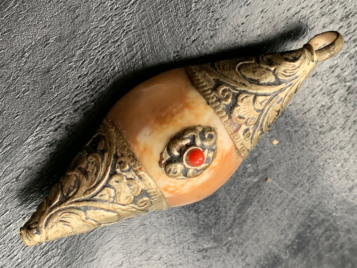 Pendentif artisanal du Népal en coquillage sertis en métal avec de jolies gravures et une perle de corail ! De 60 millimètres de hauteur x 23 mm de largeur x 16 d'épaisseur. Vendu avec cordon noir réglable offert, parfait !