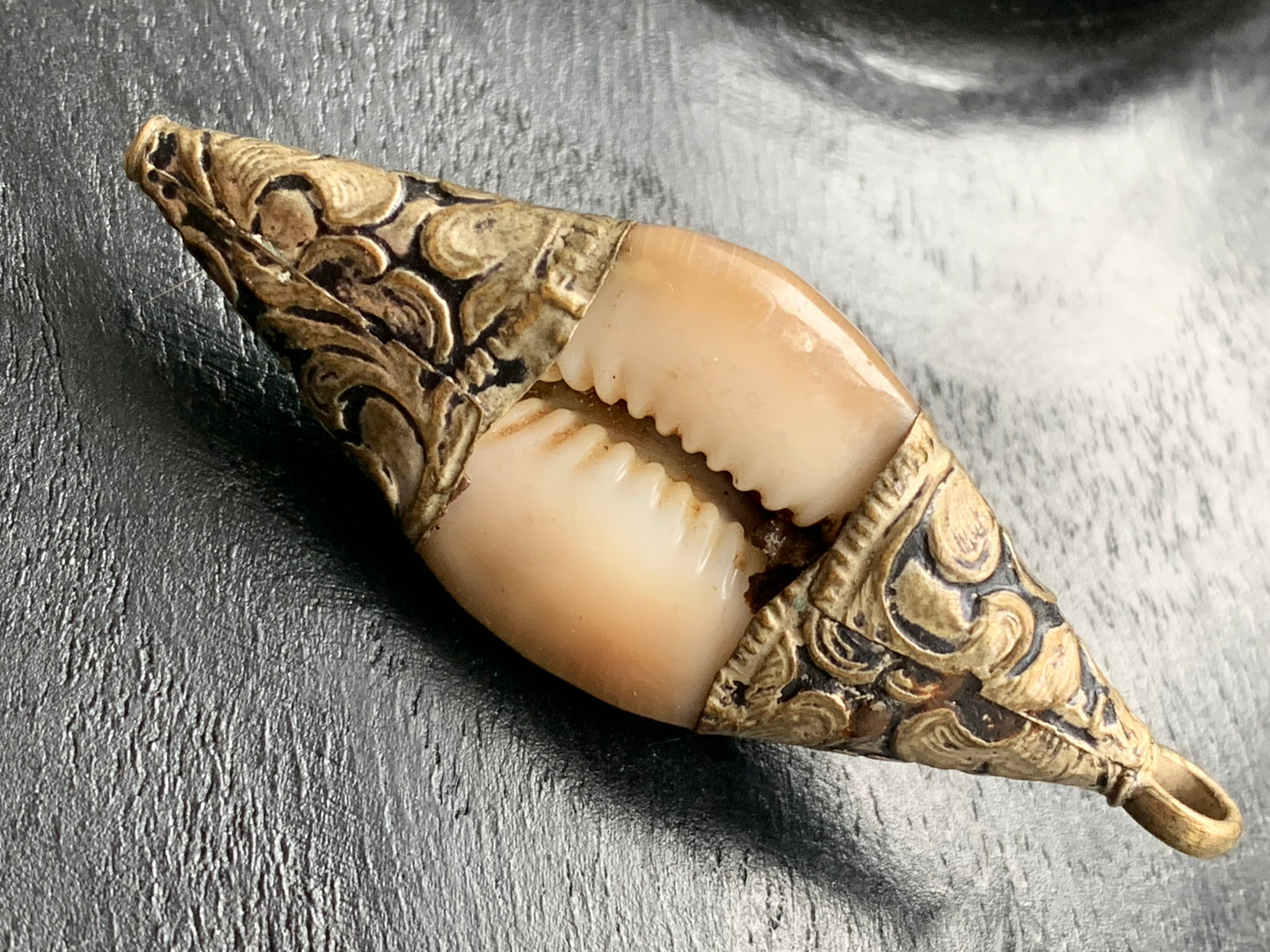 Pendentif artisanal du Népal en coquillage sertis en métal avec de jolies gravures et une perle de corail ! De 60 millimètres de hauteur x 23 mm de largeur x 16 d'épaisseur. Vendu avec cordon noir réglable offert, parfait !