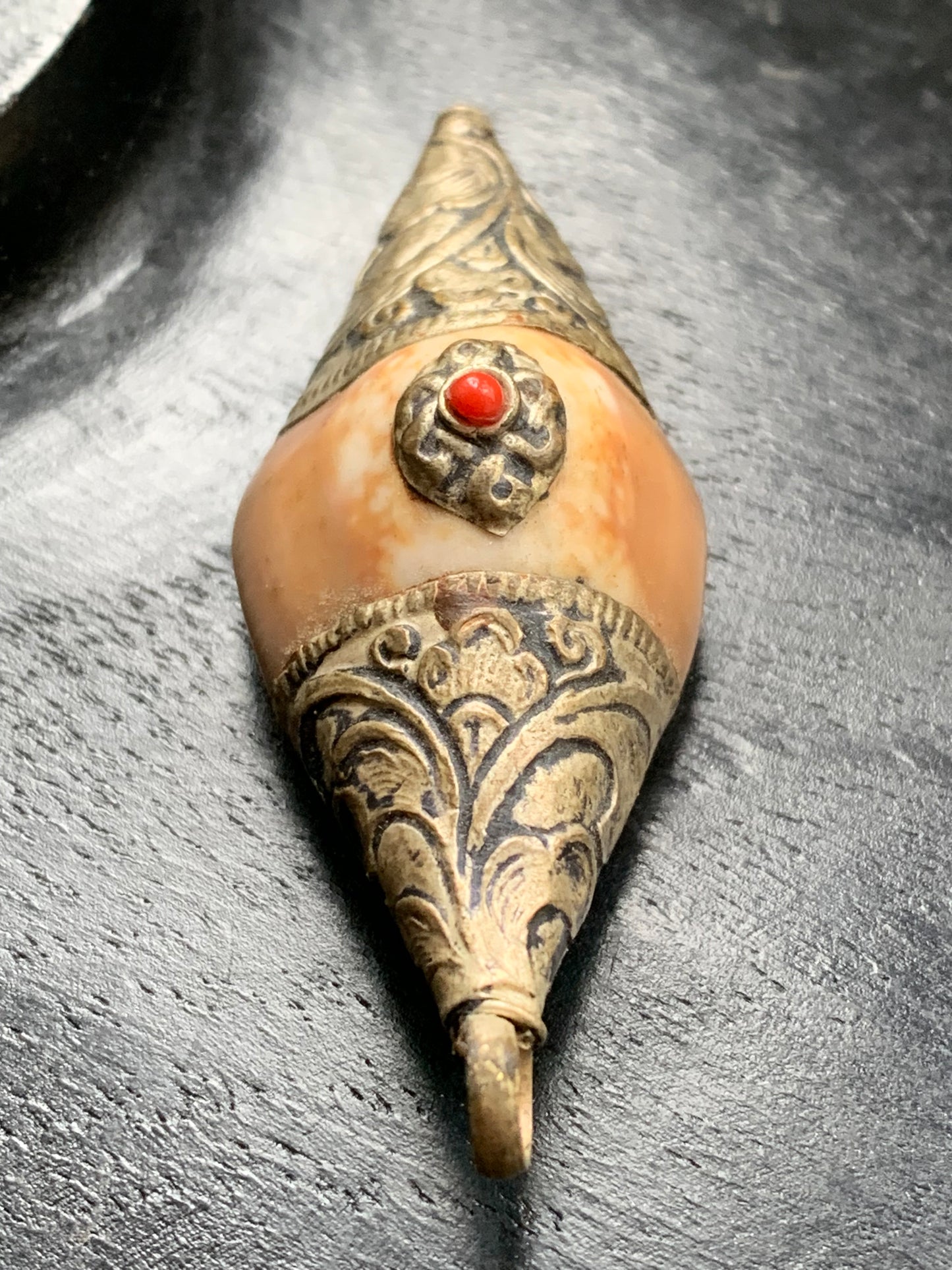 Pendentif artisanal du Népal en coquillage sertis en métal avec de jolies gravures et une perle de corail ! De 60 millimètres de hauteur x 23 mm de largeur x 16 d'épaisseur. Vendu avec cordon noir réglable offert, parfait !