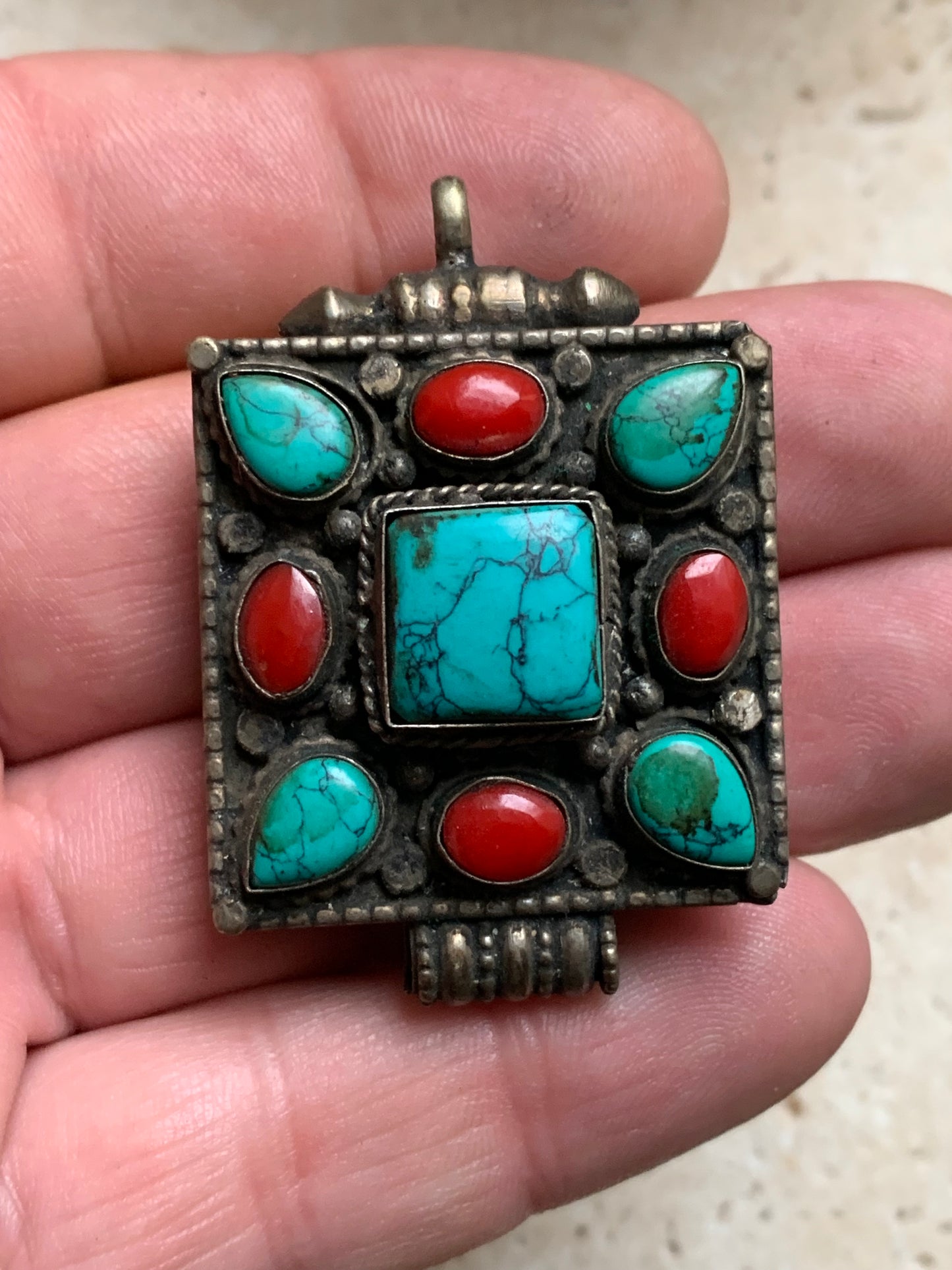 Pendentif/ Reliquaire artisanal du Népal avec pierres de turquoise et de corail sertis sur méta ! De 50 millimètres de hauteur x 35 mm de largeur x 17 d'épaisseur. Vendu avec cordon noir réglable offert, parfait !