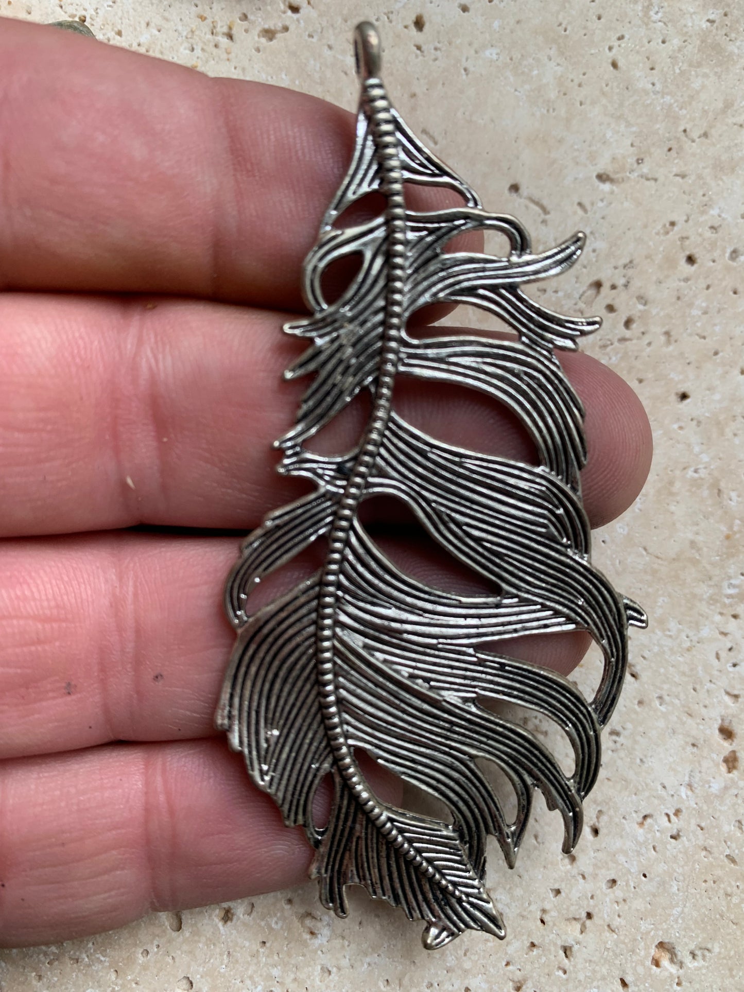 Pendentif en métal argenté en forme de plume. De 85 x 40 x 5 millimètres. Vendu avec cordon noir réglable offert, parfait !