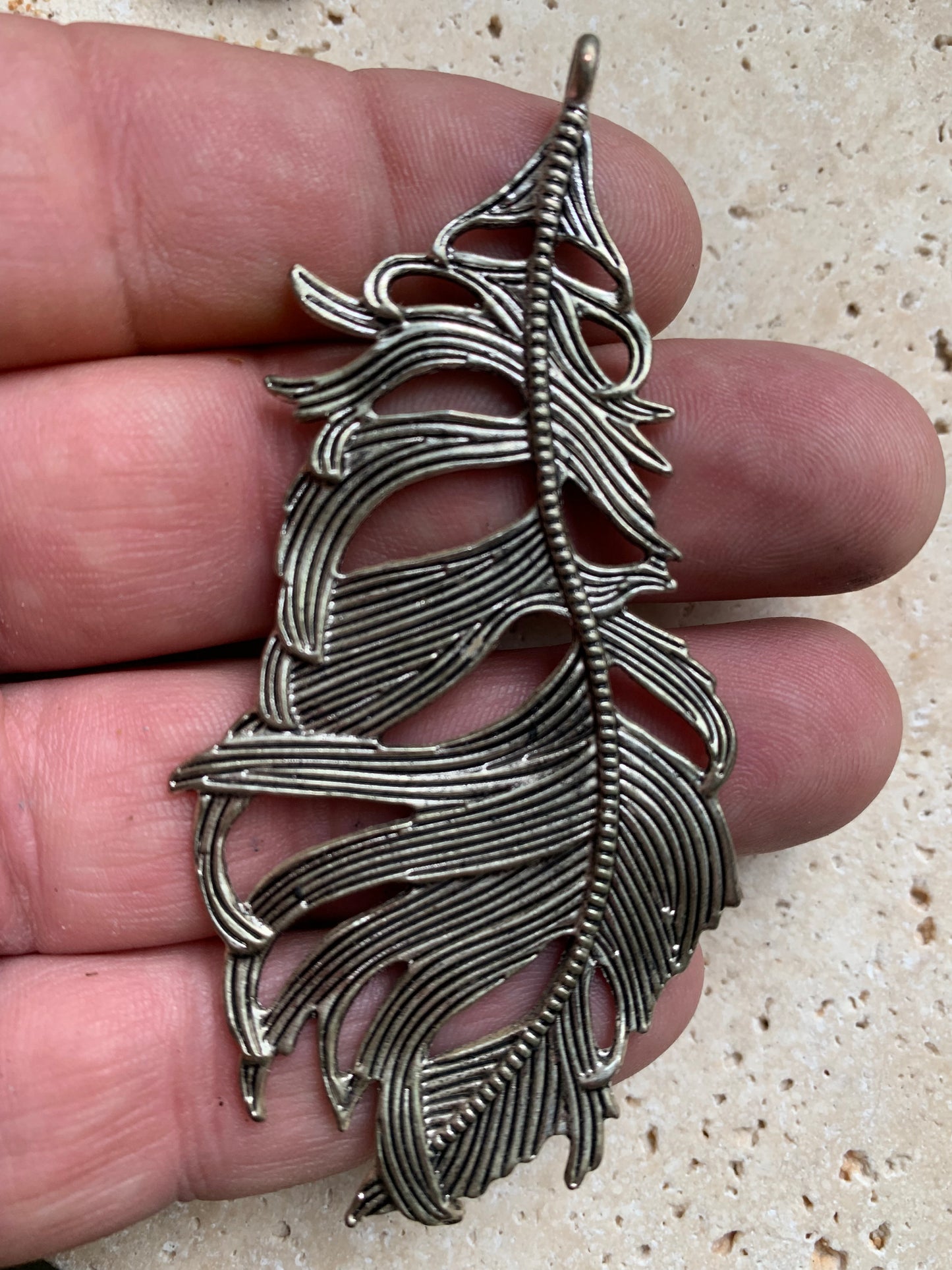 Pendentif en métal argenté en forme de plume. De 85 x 40 x 5 millimètres. Vendu avec cordon noir réglable offert, parfait !