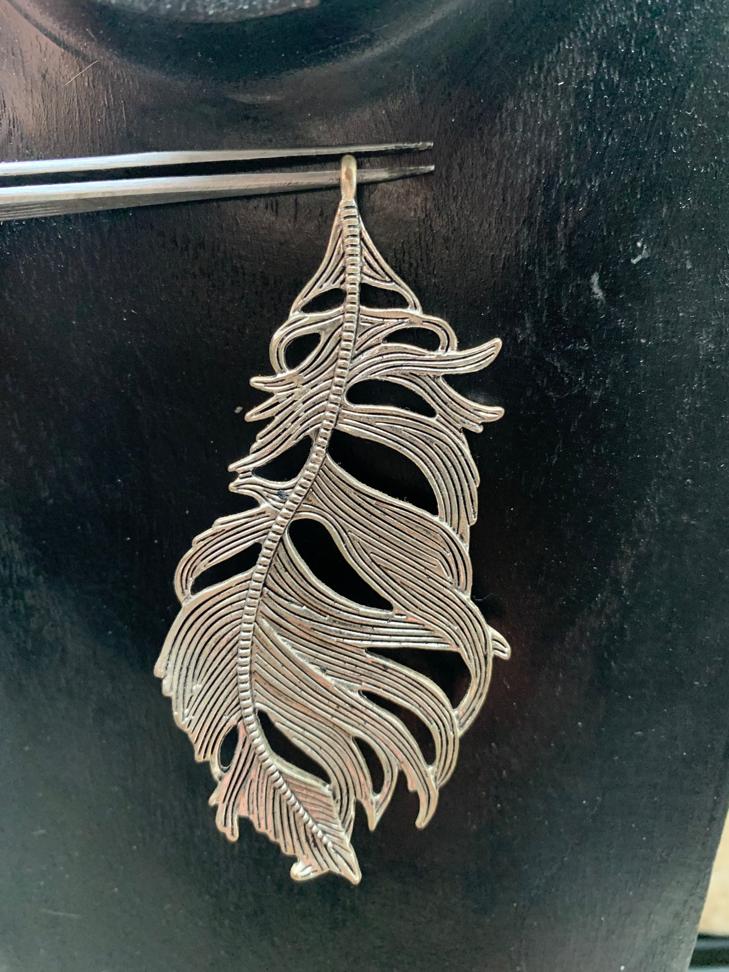 Pendentif en métal argenté en forme de plume. De 85 x 40 x 5 millimètres. Vendu avec cordon noir réglable offert, parfait !