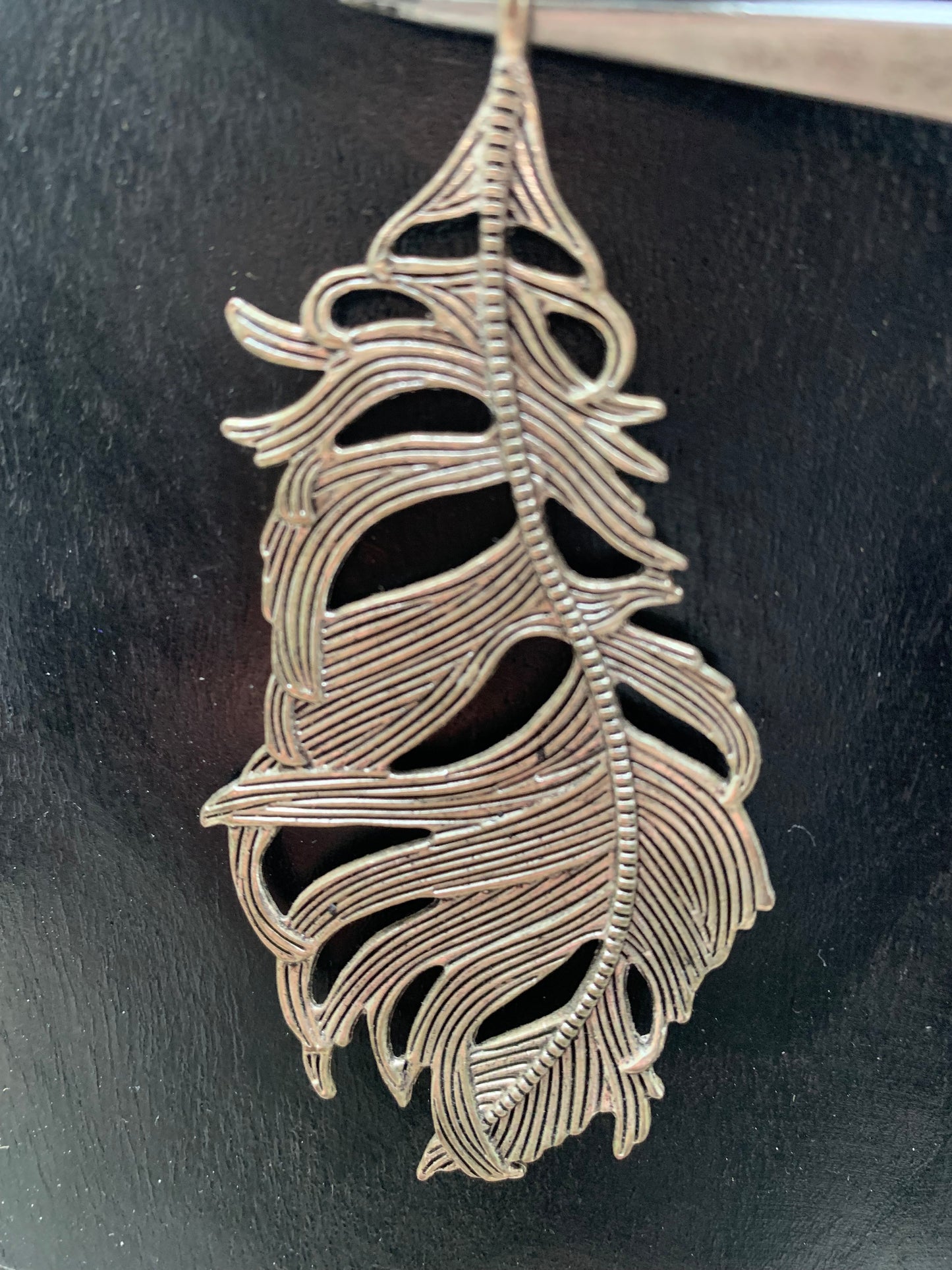 Pendentif en métal argenté en forme de plume. De 85 x 40 x 5 millimètres. Vendu avec cordon noir réglable offert, parfait !