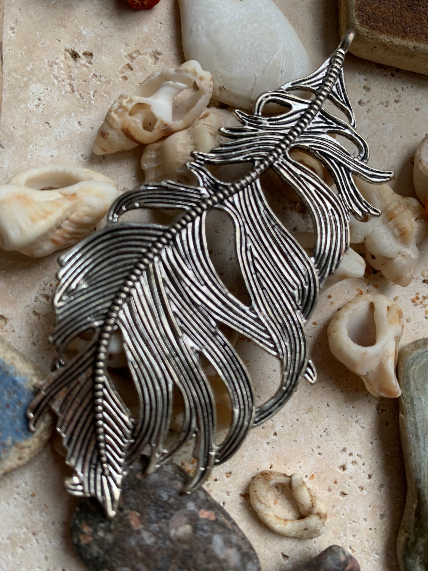 Pendentif en métal argenté en forme de plume. De 85 x 40 x 5 millimètres. Vendu avec cordon noir réglable offert, parfait !