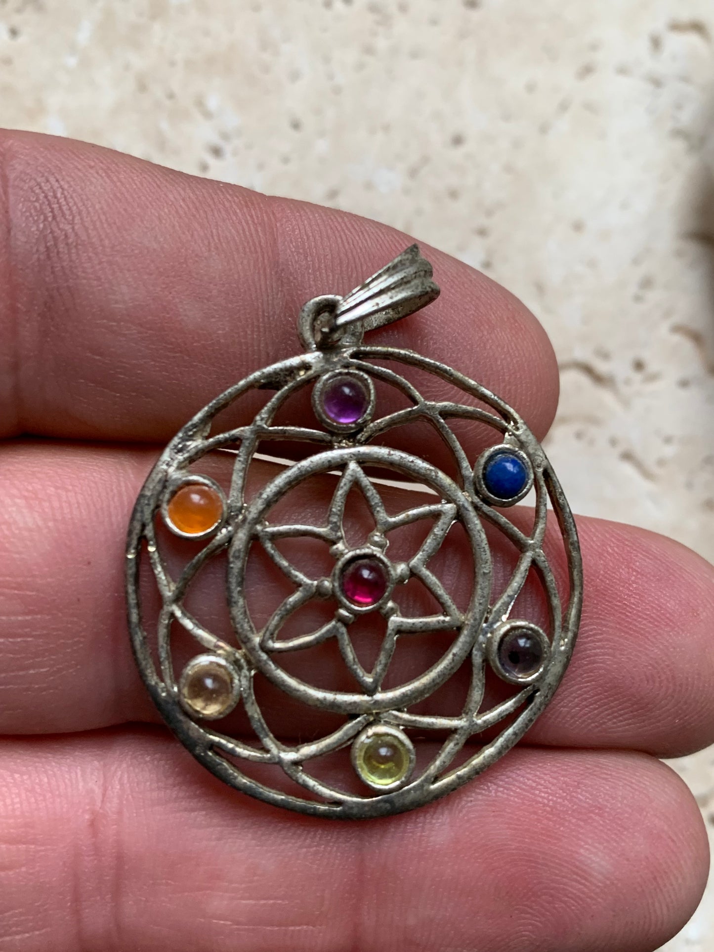 Pendentif '7 chakras' de 35 millimètres de diamètre, en métal argenté (laiton). Vendu avec cordon réglable de couleur noire !