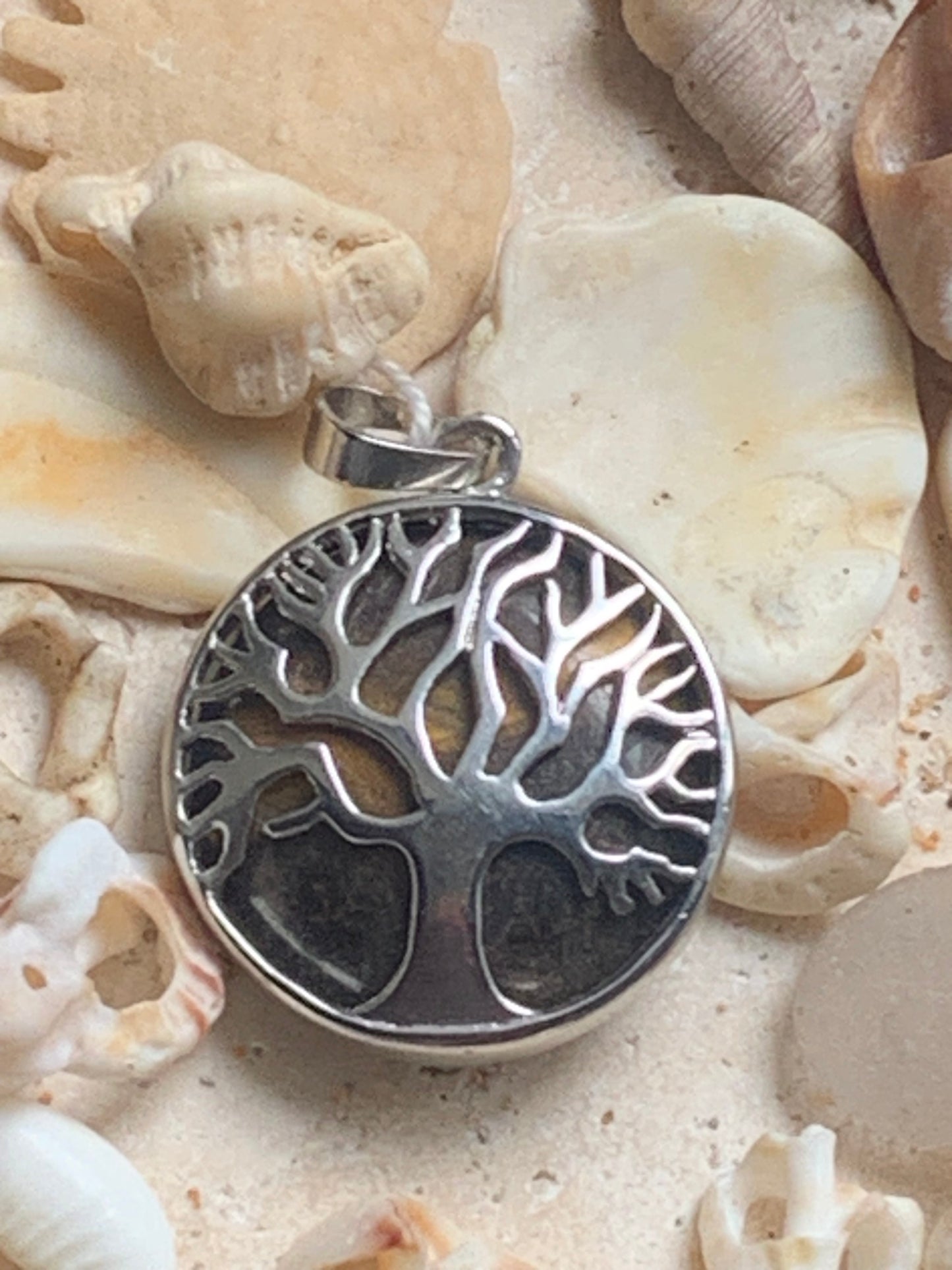 Pendentif en métal argenté 'Arbre de vie' avec un oeil de tigre en fond, de 27 mm de diamètre. Vendu avec cordon noir réglable, parfait !