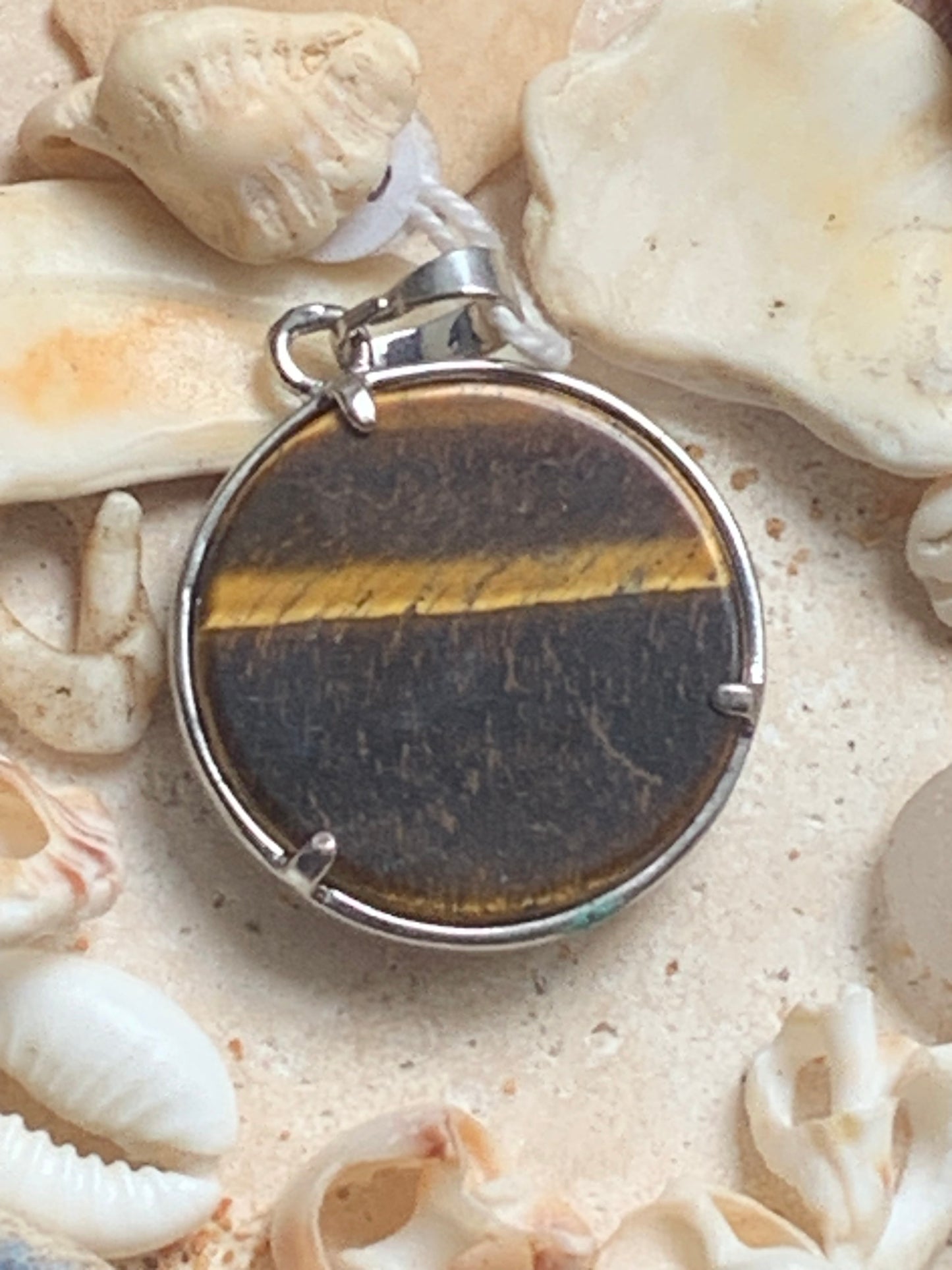 Pendentif en métal argenté 'Arbre de vie' avec un oeil de tigre en fond, de 27 mm de diamètre. Vendu avec cordon noir réglable, parfait !