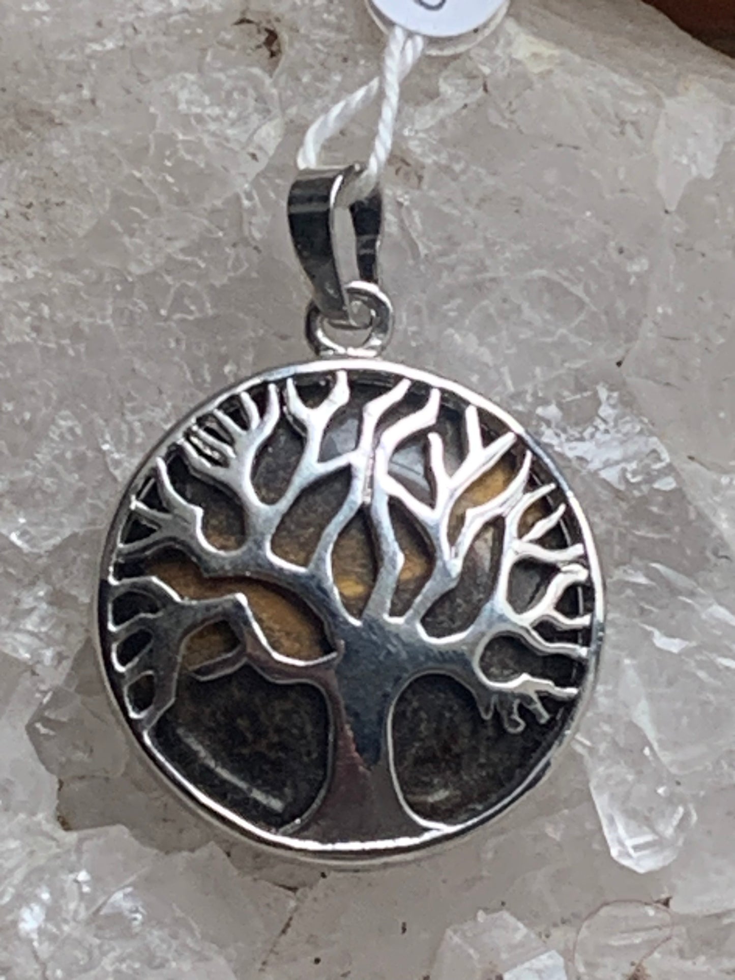Pendentif en métal argenté 'Arbre de vie' avec un oeil de tigre en fond, de 27 mm de diamètre. Vendu avec cordon noir réglable, parfait !