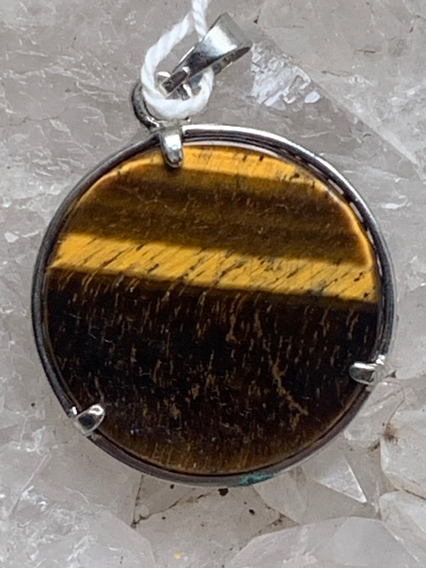 Pendentif en métal argenté 'Arbre de vie' avec un oeil de tigre en fond, de 27 mm de diamètre. Vendu avec cordon noir réglable, parfait !
