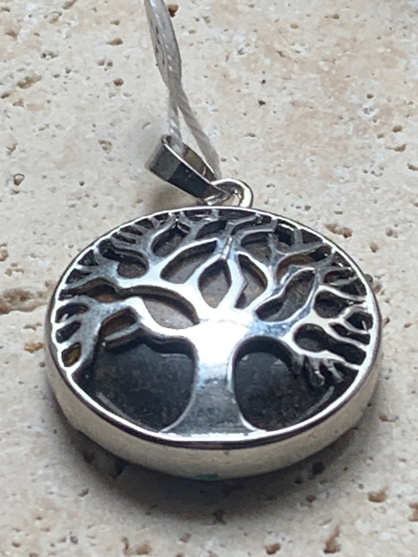 Pendentif en métal argenté 'Arbre de vie' avec un oeil de tigre en fond, de 27 mm de diamètre. Vendu avec cordon noir réglable, parfait !