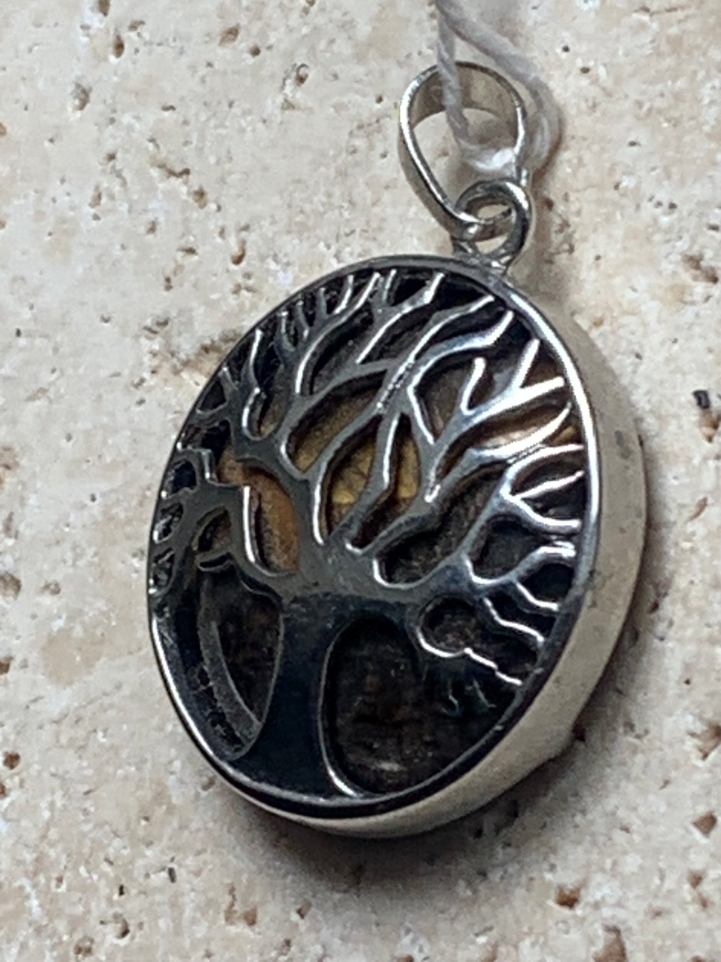 Pendentif en métal argenté 'Arbre de vie' avec un oeil de tigre en fond, de 27 mm de diamètre. Vendu avec cordon noir réglable, parfait !