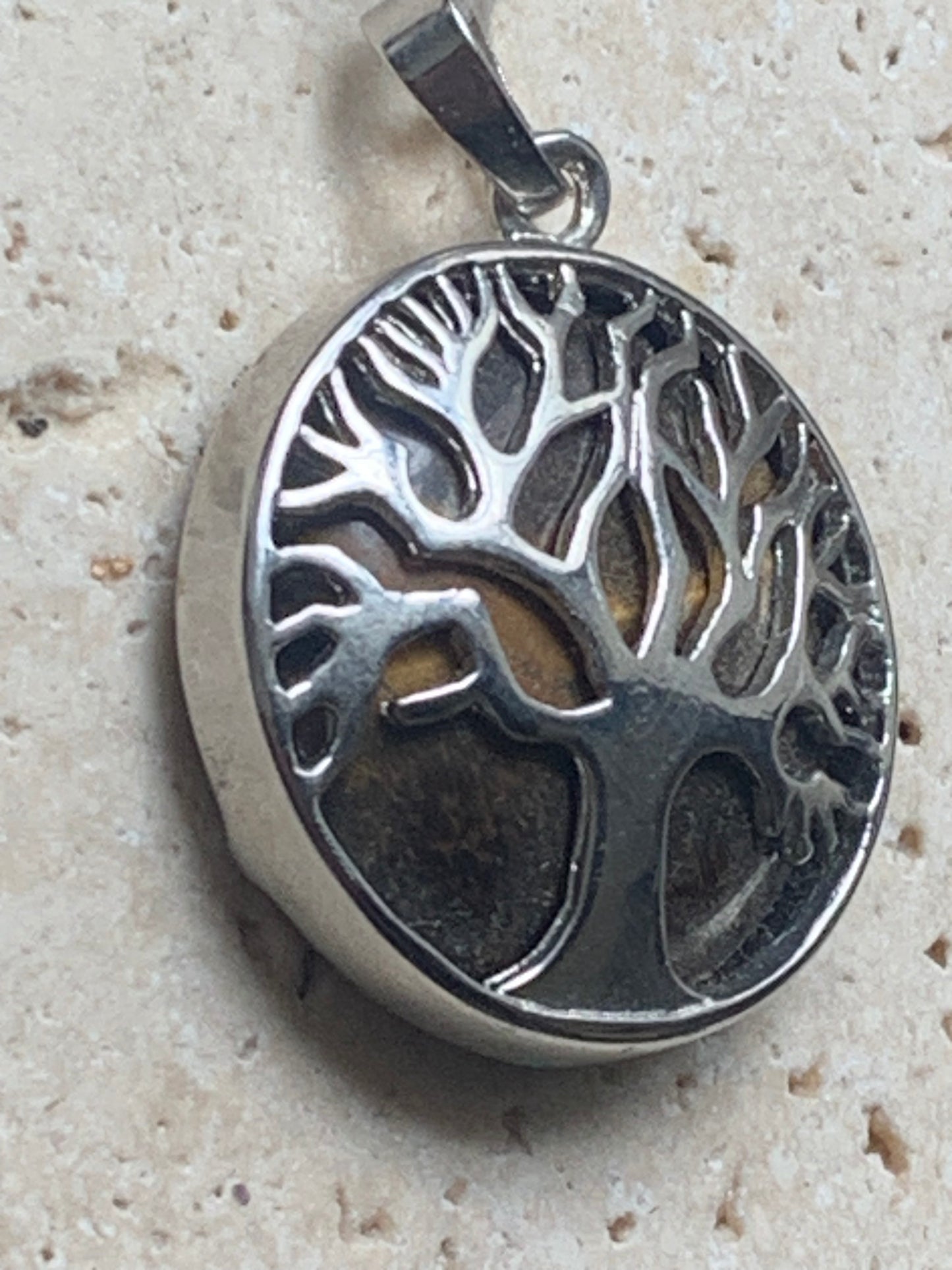 Pendentif en métal argenté 'Arbre de vie' avec un oeil de tigre en fond, de 27 mm de diamètre. Vendu avec cordon noir réglable, parfait !