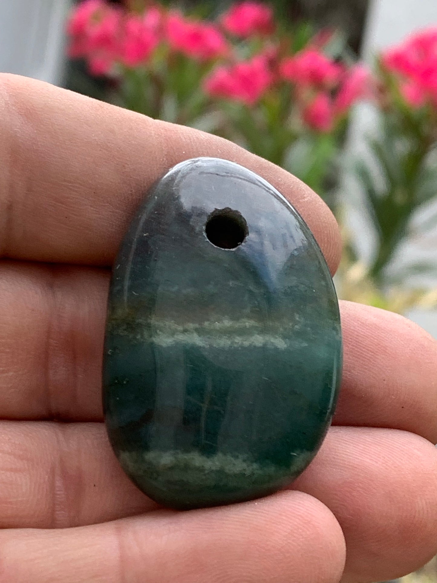 Jade, galet percé 43 mm de hauteur x 30 de largeur x 12 d'épaisseur. Vendu avec cordon réglable de couleur noire.