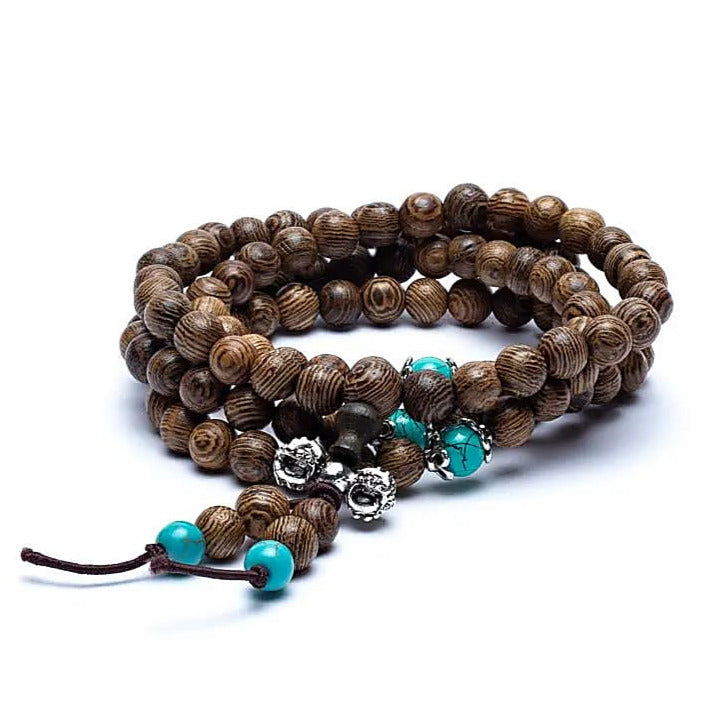 Mala de bois avec perles ornementales et finition avec 'Dorje', de 108 perles de ± 6 millimètres. Taille de 60 centimètres de longueur environ. Superbe pièce avec pochette de rangement offerte. Fait en Inde !