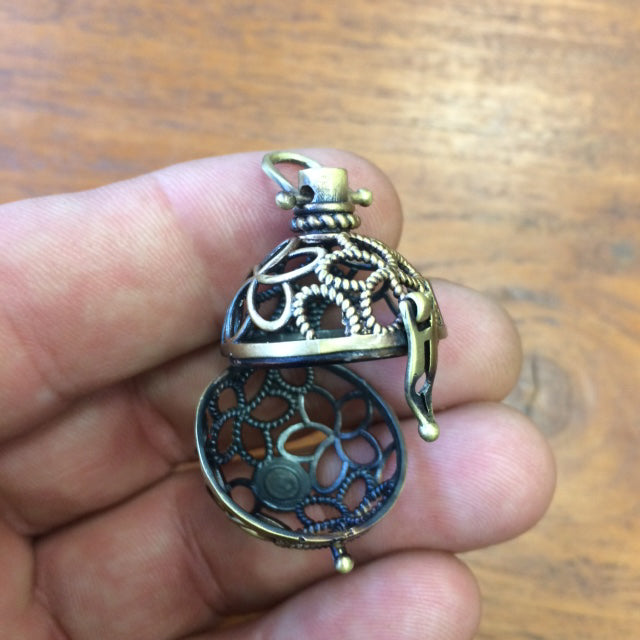 Pendentif/ Cage à pierre, peut servir de Bolas (pendentif de grossesse) ou pour perle de lave pour huile essentielle ! 2,5 centimètres de diamètre. Fait en laiton ! Vendu avec une perle de lave de 10mm !