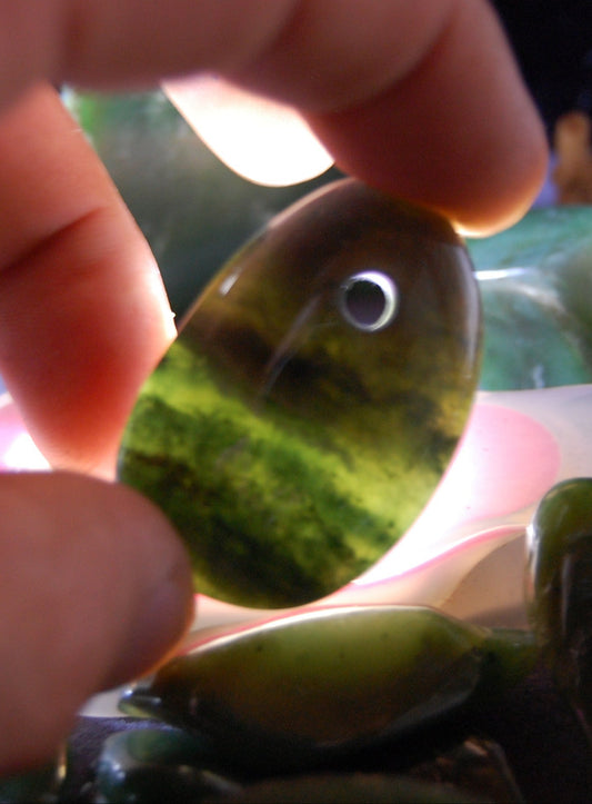 Jade, galet percé 43 mm de hauteur x 30 de largeur x 12 d'épaisseur. Vendu avec cordon réglable de couleur noire.
