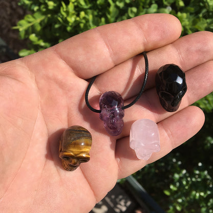 Pendentif en forme de crâne, symbole de la connaissance ! De 18 millimètres de hauteur x 16 mm de largeur. Pierre au choix : Améthyste, Obsidienne, Quartz rose, Oeil de tigre. Vendu avec cordon noir réglable offert, parfait !