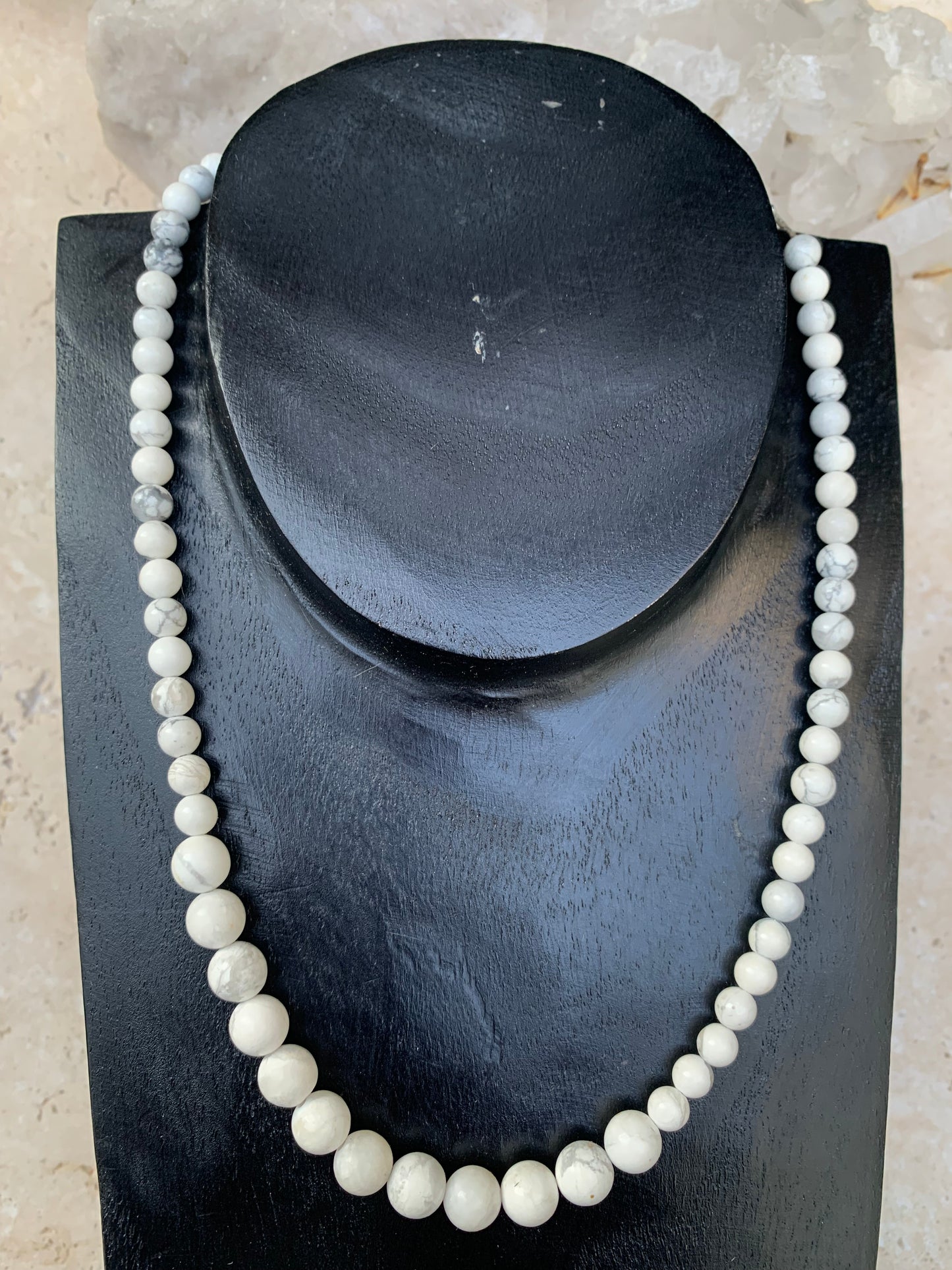 Howlite, 'collier/ chute de perle', de forme ronde de 4 à 10 millimètres de diamètre. 44 centimètres de longueur + 4 cm de rajout en chaînette. Fermoir de type 'mousqueton'. Très belle pièce !