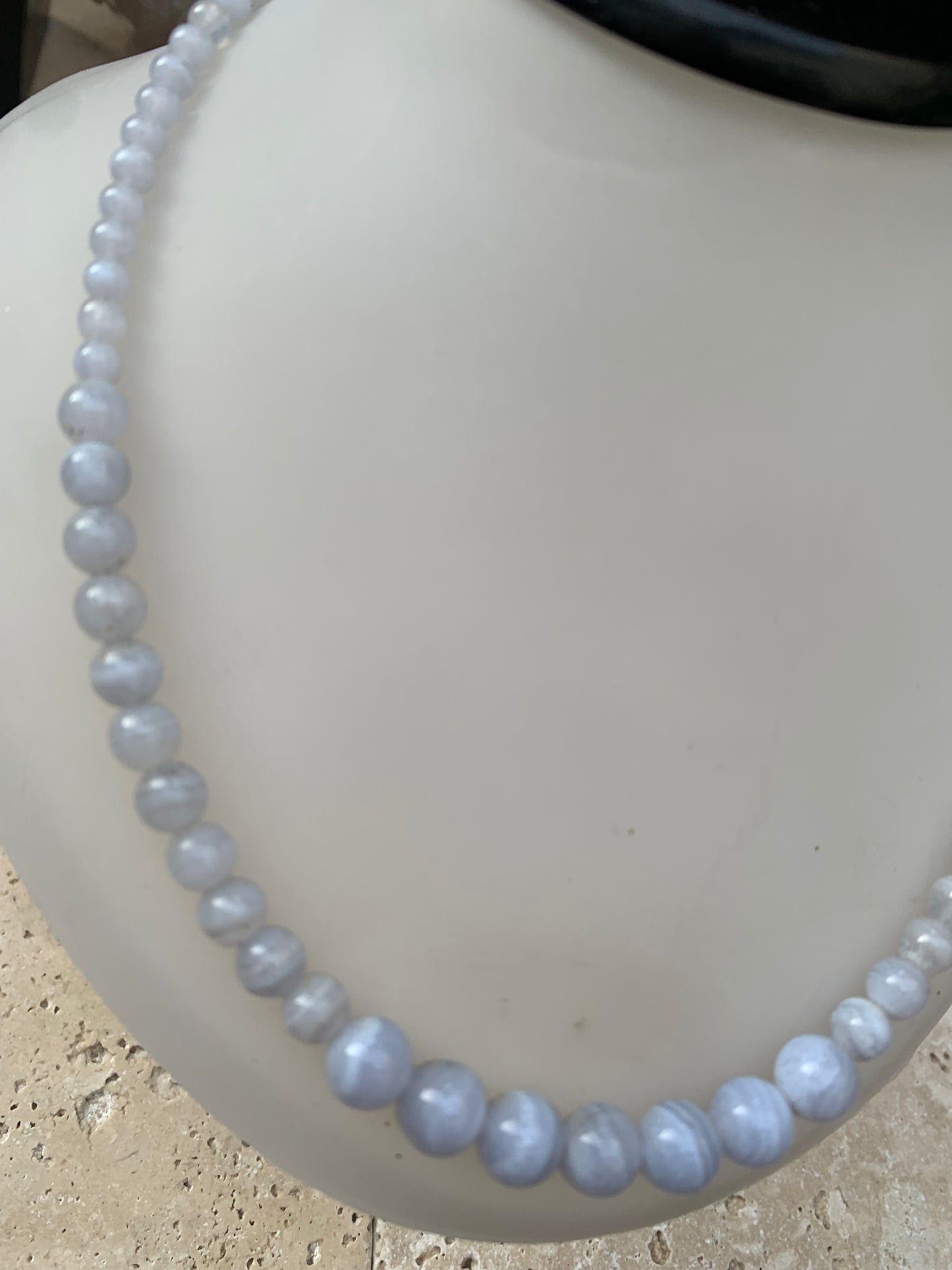 Agate Blue Lace, 'collier/ chute de perle', de forme ronde de 4 à 10 millimètres de diamètre. 44 centimètres de longueur + 4 cm de rajout en chaînette. Fermoir de type 'mousqueton'. Très belle pièce !