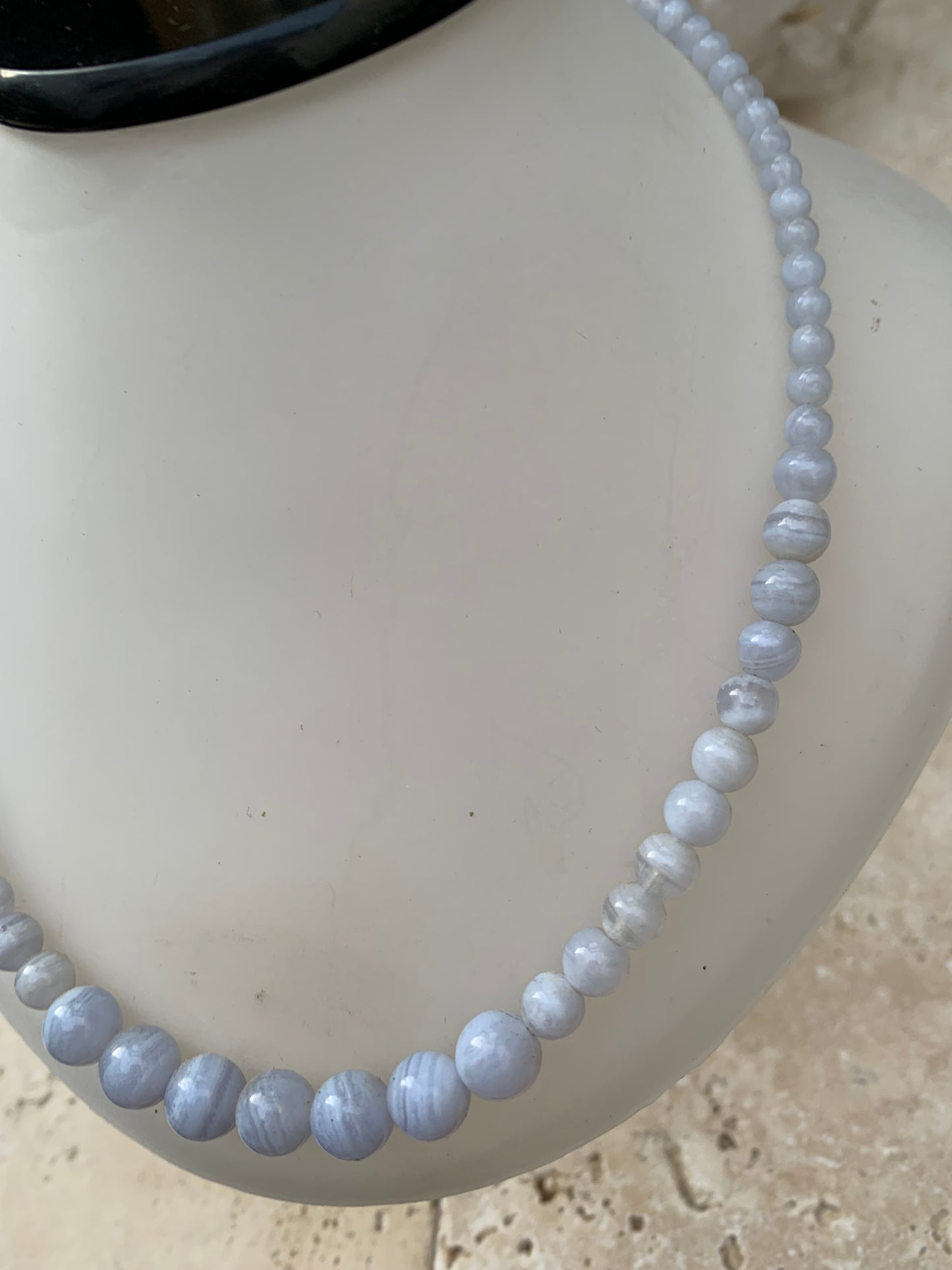 Agate Blue Lace, 'collier/ chute de perle', de forme ronde de 4 à 10 millimètres de diamètre. 44 centimètres de longueur + 4 cm de rajout en chaînette. Fermoir de type 'mousqueton'. Très belle pièce !