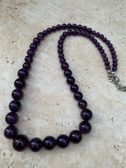 Améthyste, 'collier/ chute de perle', de forme ronde de 4 à 10 millimètres de diamètre. 50 centimètres de longueur + 4 cm de rajout en chaînette. Fermoir de type 'mousqueton'. Très belle pièce !
