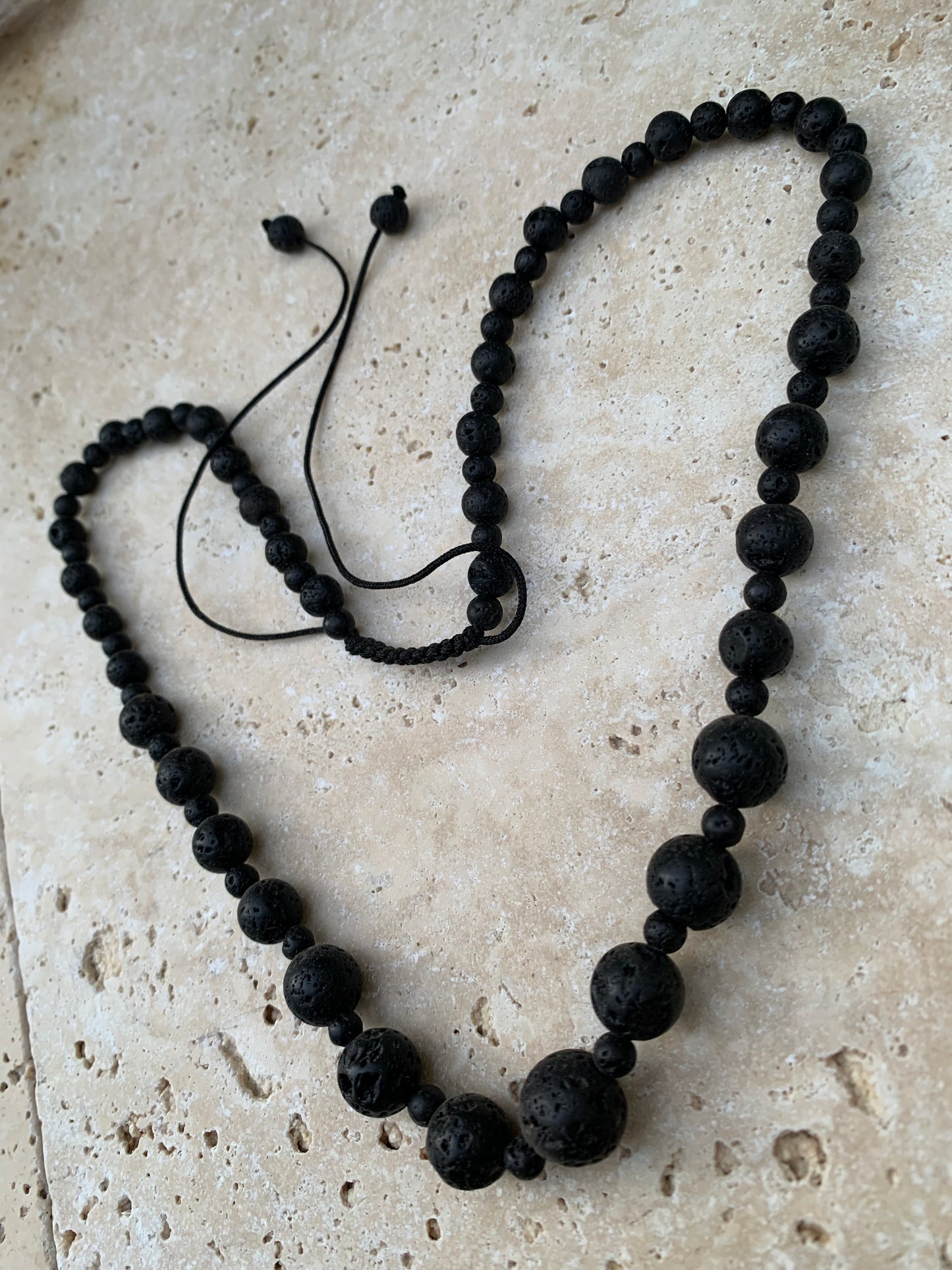 Pierre de lave, 'collier/ chute de perle', de forme ronde de 4 à 10 millimètres de diamètre. 50 centimètres de longueur. Fermeture coullissante de type 'Mala'. très belle pièce !