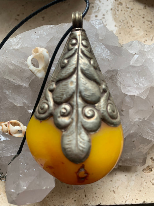 Pendentif en Copal sertis en métal avec de majestueuses gravures. Impressionante pièce de 85 x 50 x 30 millimètres, fait au Népal 🇳🇵. Bijoux ethnique, unique et authentique vendu avec cordon coulisant !