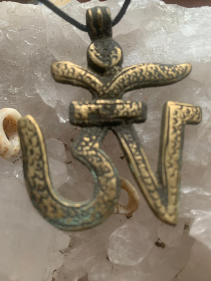 Om, symbole sacré en métal (laiton), taille de 60x50x10 millimètres. Pièce authentique et unique faîte au Népal. Livré avec cordon coulissant, prêt à porté ou à offrir !