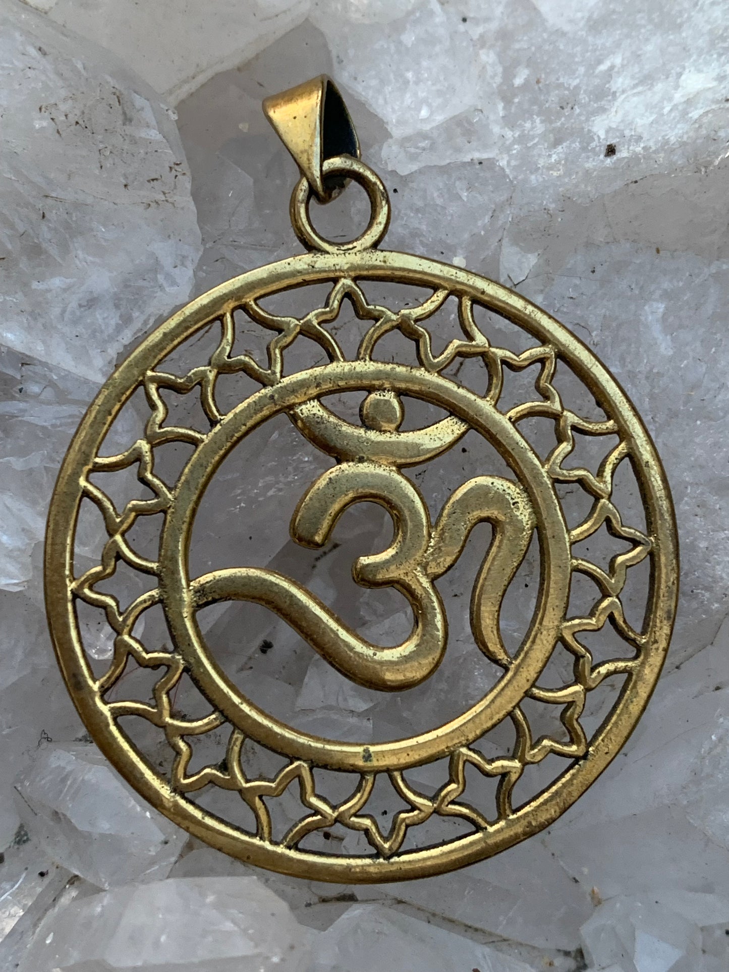 Om, pendentif en laiton doré de  3,6 centimètres de diamètre, vendu avec cordon noir réglable ! Tel un souffle ancien suspendu au creux du cœur, ce pendentif en laiton doré célèbre le symbole sacré Om, vibration originelle de l’univers !