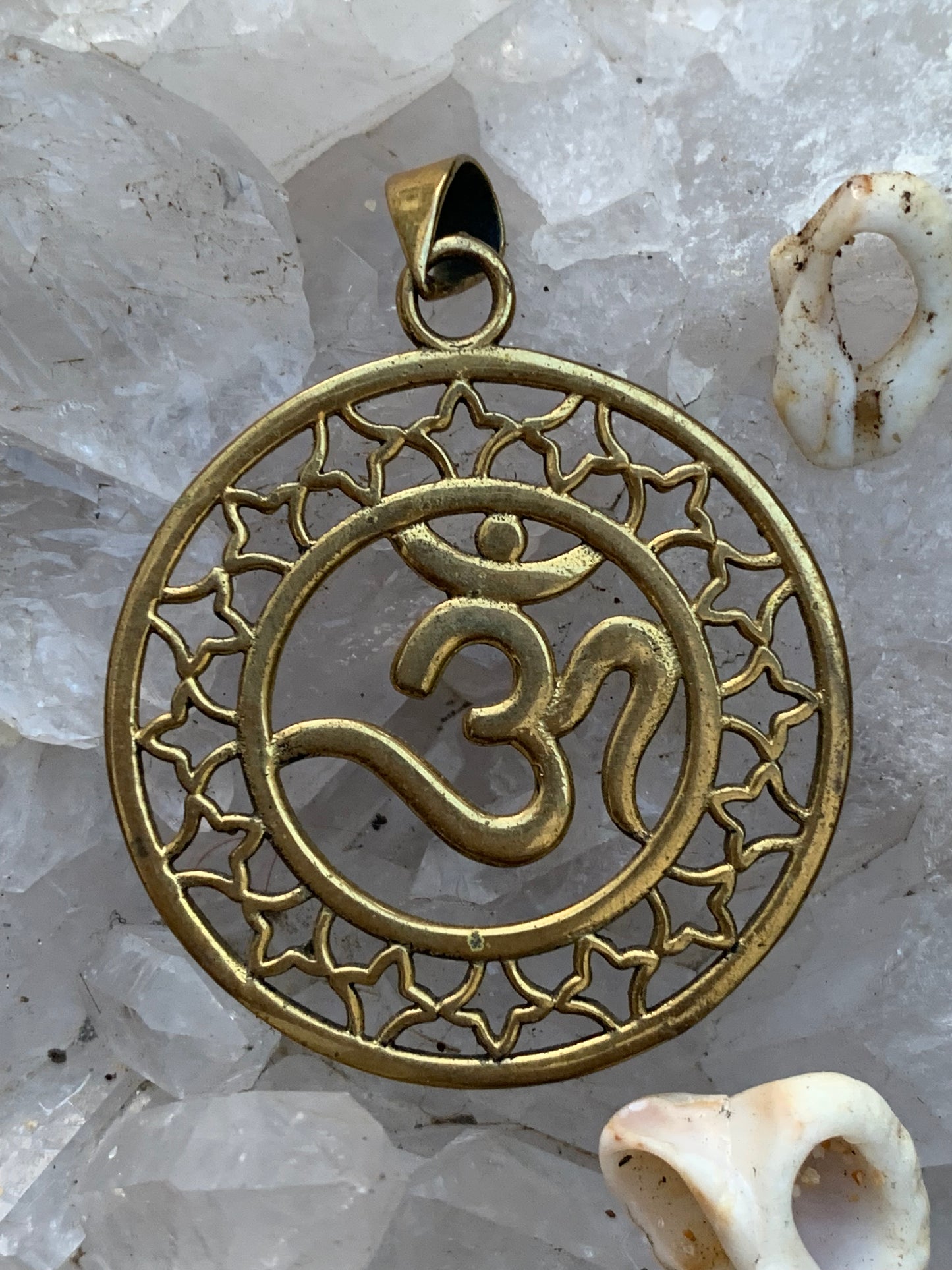 Om, pendentif en laiton doré de  3,6 centimètres de diamètre, vendu avec cordon noir réglable ! Tel un souffle ancien suspendu au creux du cœur, ce pendentif en laiton doré célèbre le symbole sacré Om, vibration originelle de l’univers !