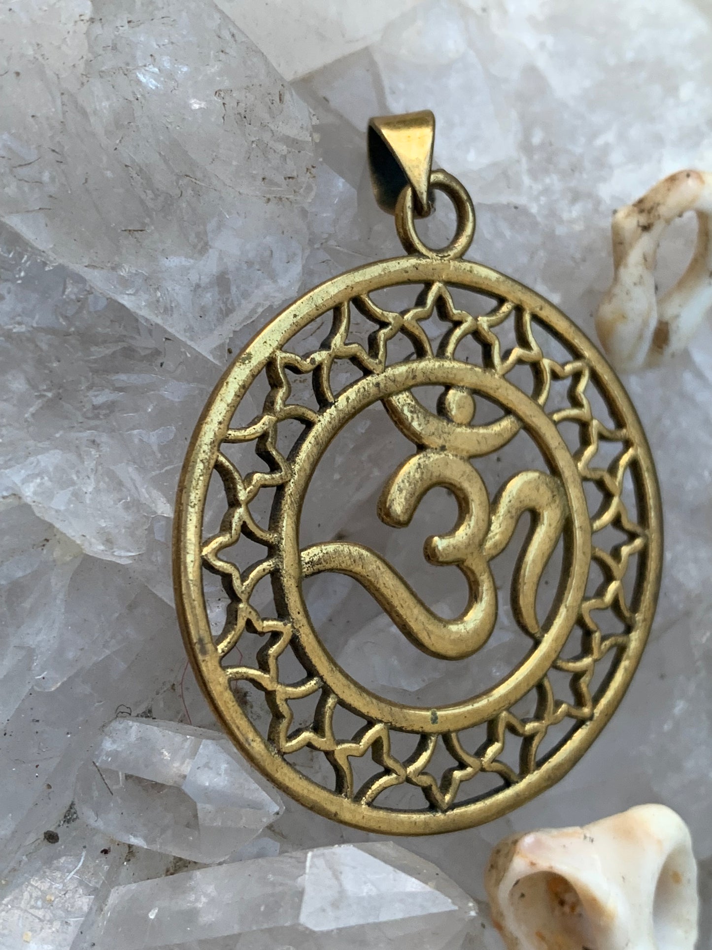 Om, pendentif en laiton doré de  3,6 centimètres de diamètre, vendu avec cordon noir réglable ! Tel un souffle ancien suspendu au creux du cœur, ce pendentif en laiton doré célèbre le symbole sacré Om, vibration originelle de l’univers !