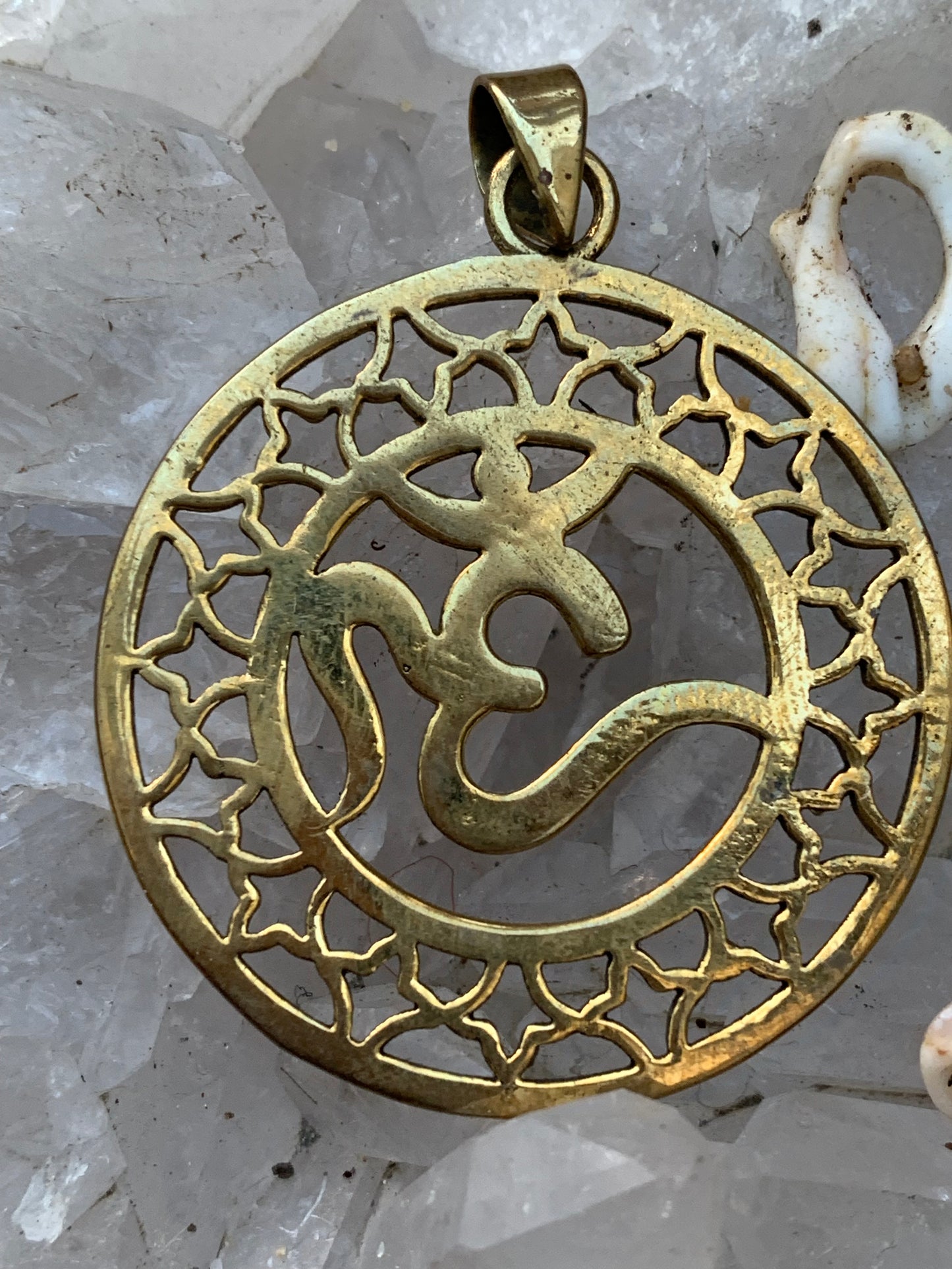 Om, pendentif en laiton doré de  3,6 centimètres de diamètre, vendu avec cordon noir réglable ! Tel un souffle ancien suspendu au creux du cœur, ce pendentif en laiton doré célèbre le symbole sacré Om, vibration originelle de l’univers !